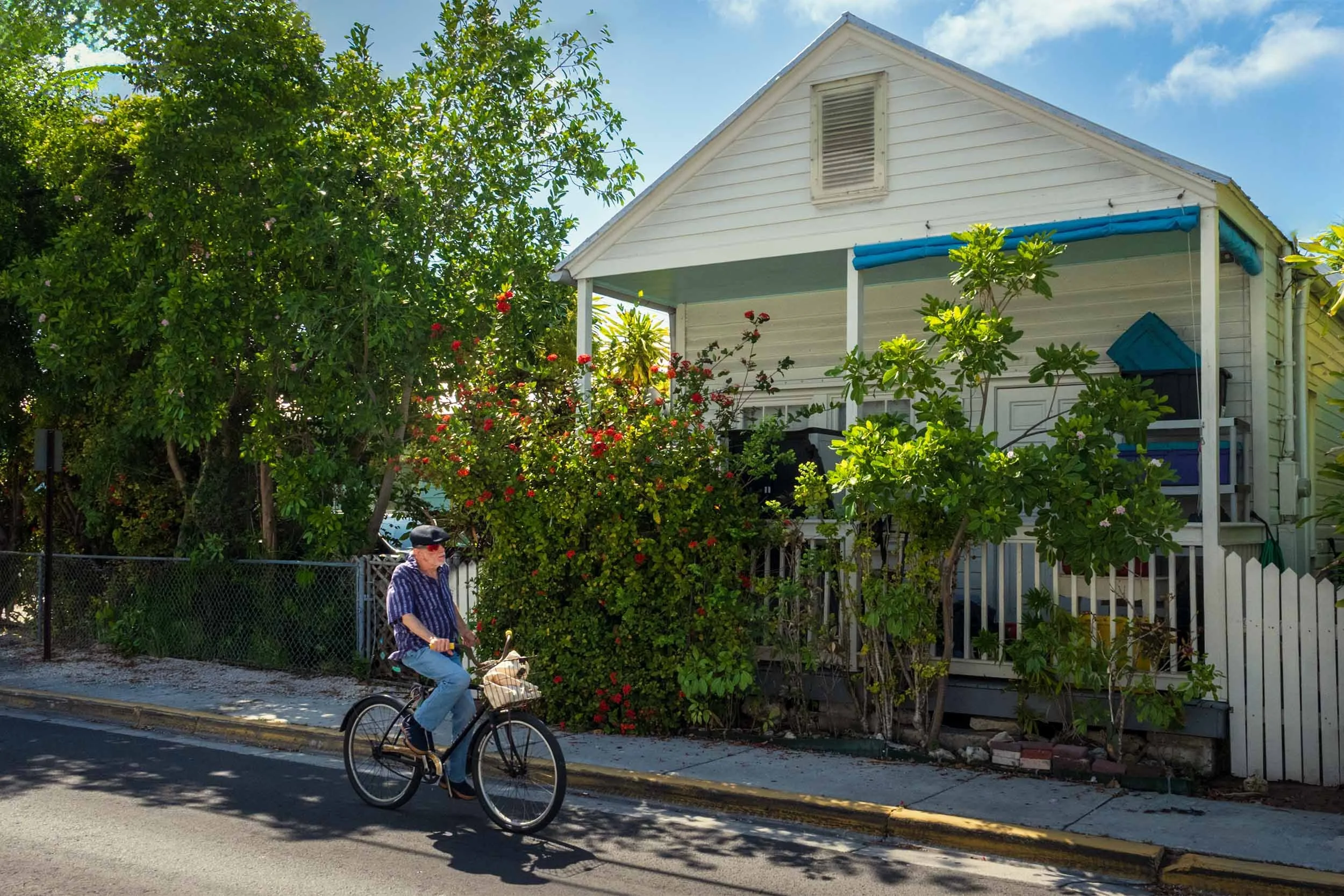 Key West neighborhood bike ride, historic white cottage, tropical garden, red flowers, Florida Keys lifestyle