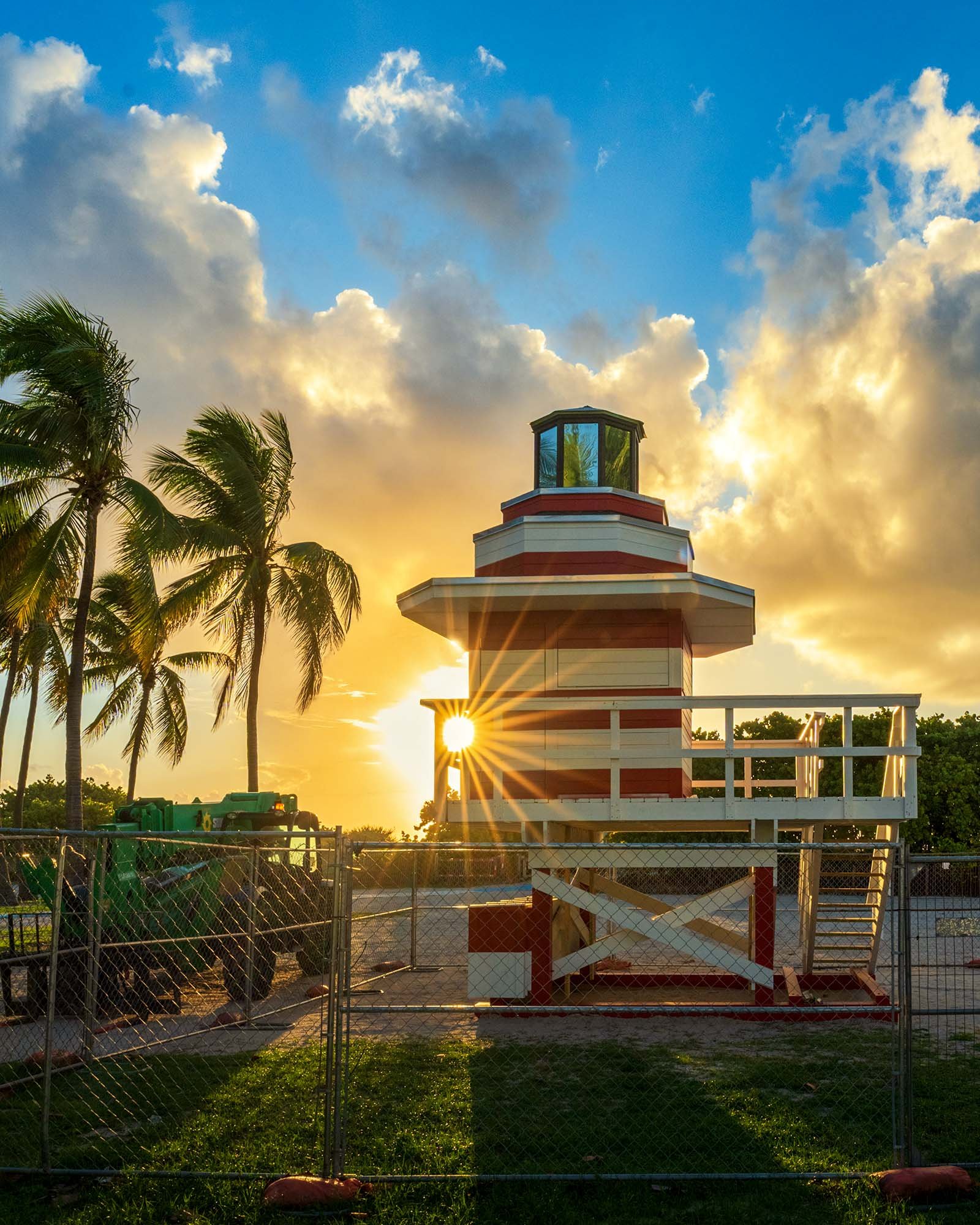 Sun shining through the new Jetty lifeguard tower behind construction fencing in Lummus Park
