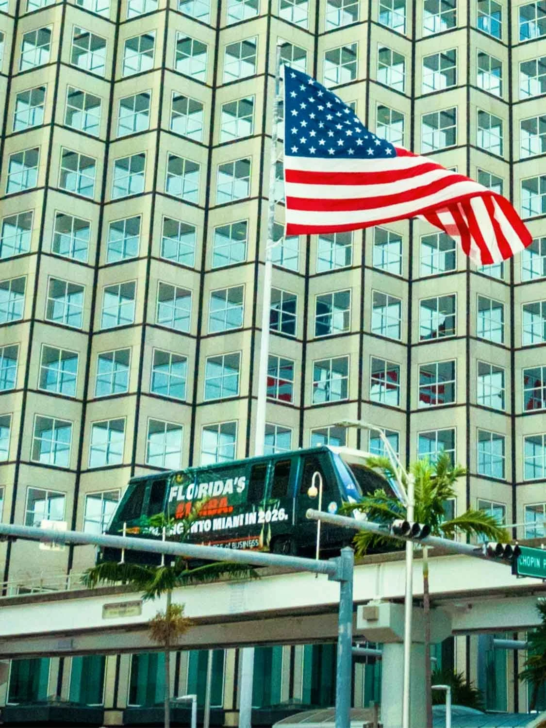 Miami downtown Metromover train Florida NBA 2026 ad American flag urban office building Brickell