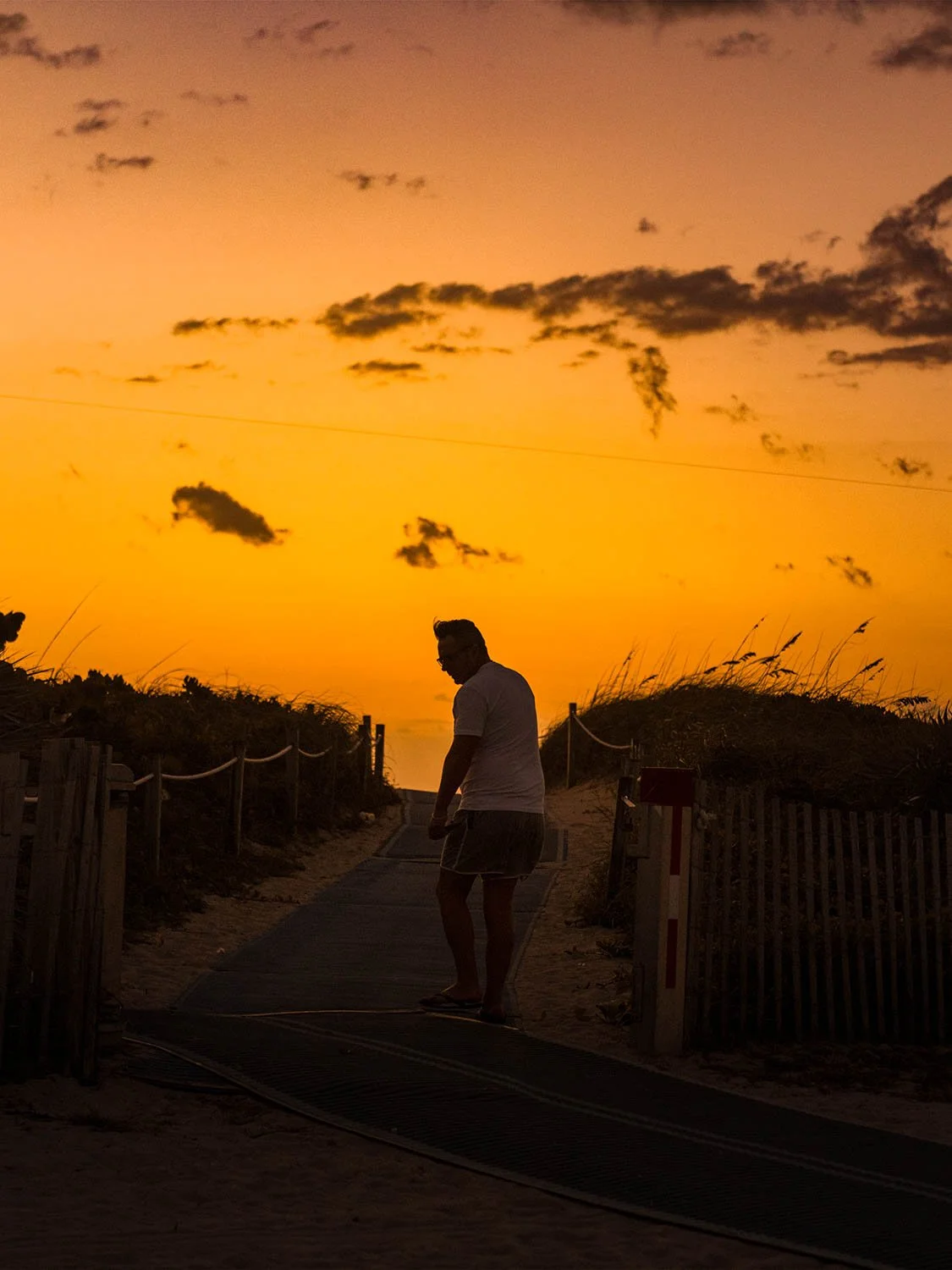 Man silhouetted on a beach boardwalk path at golden hour sunset in South Beach Miami