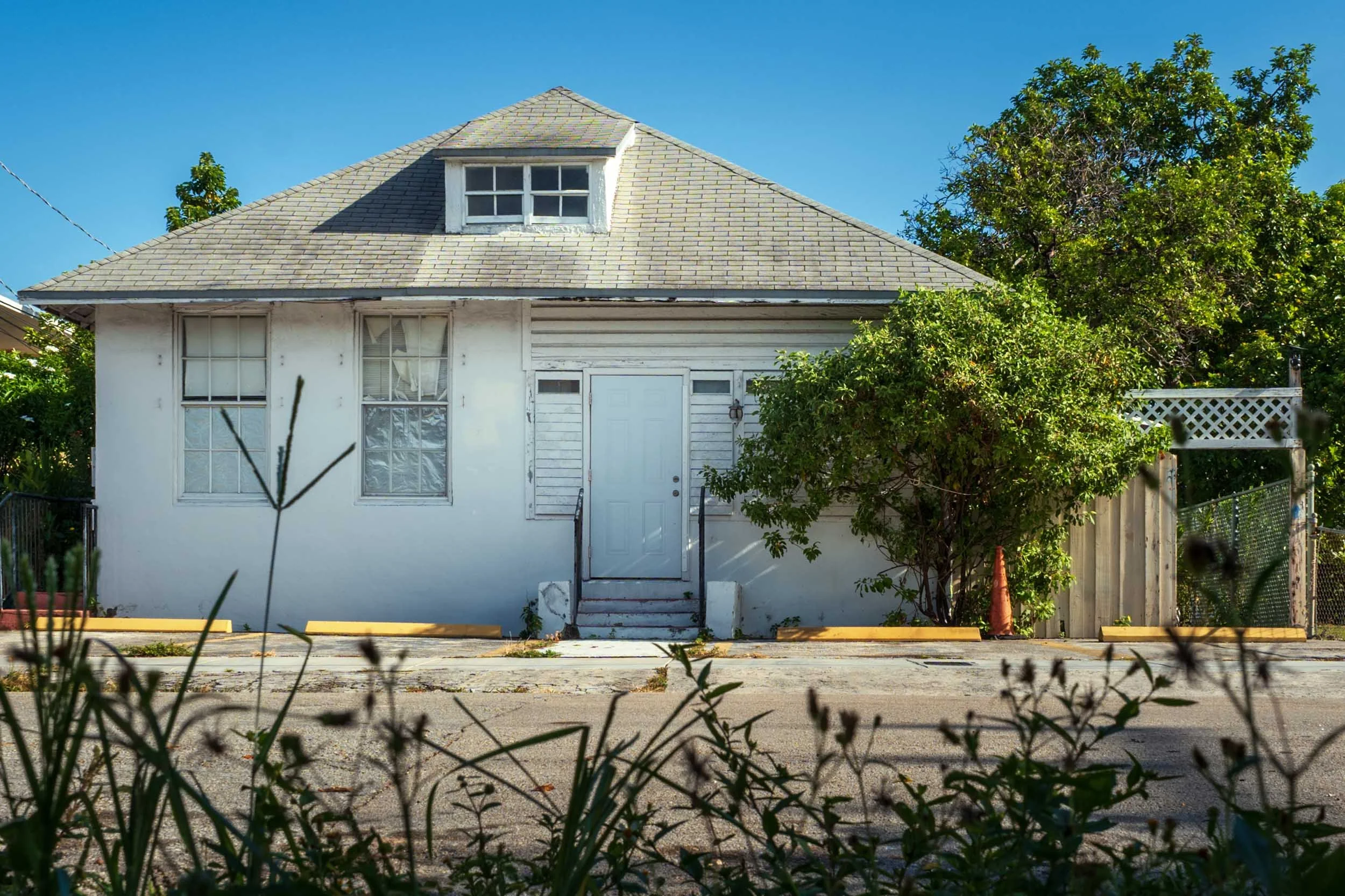 White hip-roof bungalow with a dormer window in Miami's River District