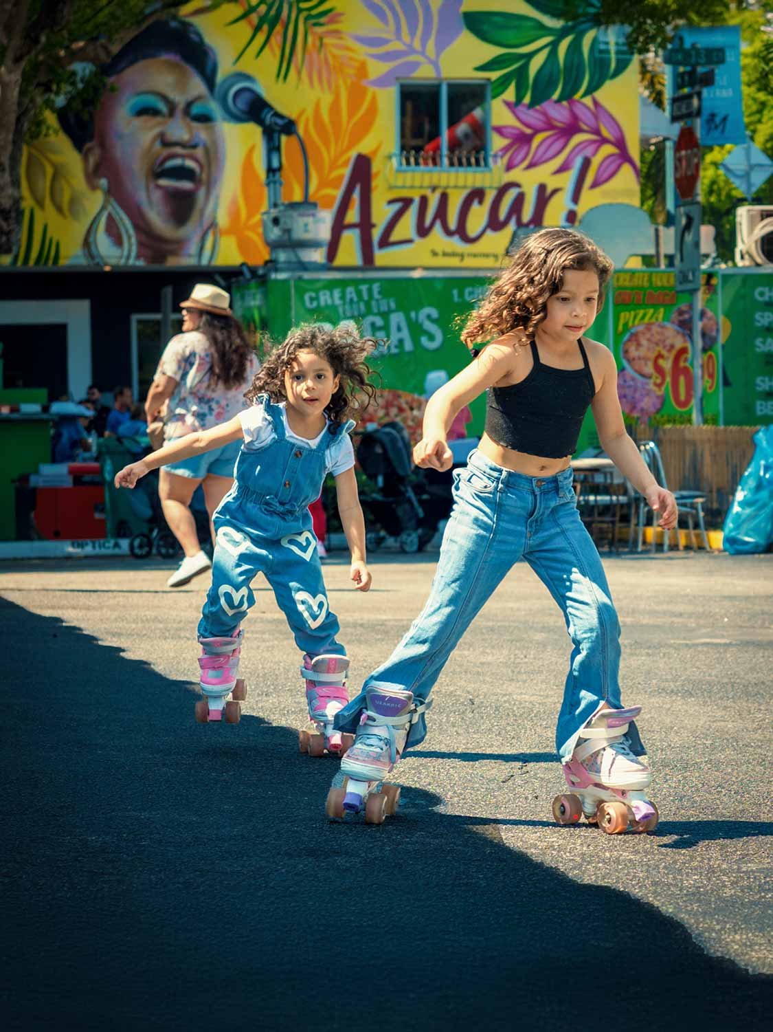Two little girls roller skating down Calle Ocho during Carnival Miami in Little Havana