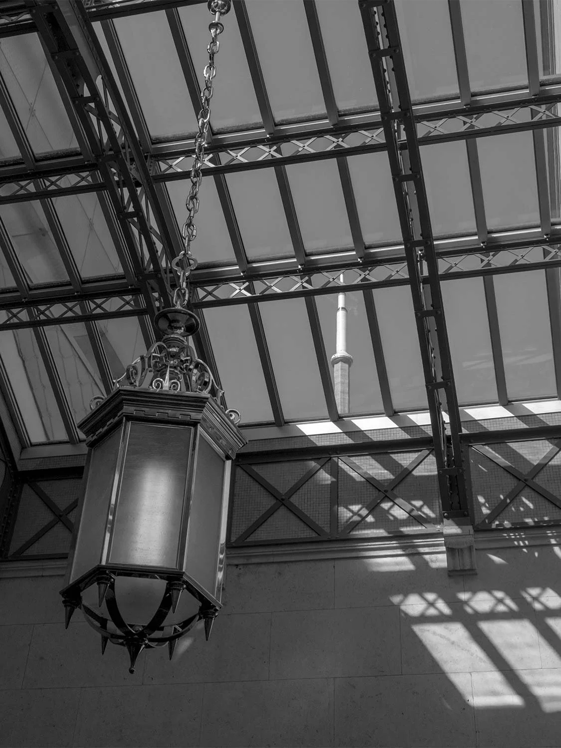 Vintage lantern inside Union Station Toronto with CN Tower visible through glass ceiling