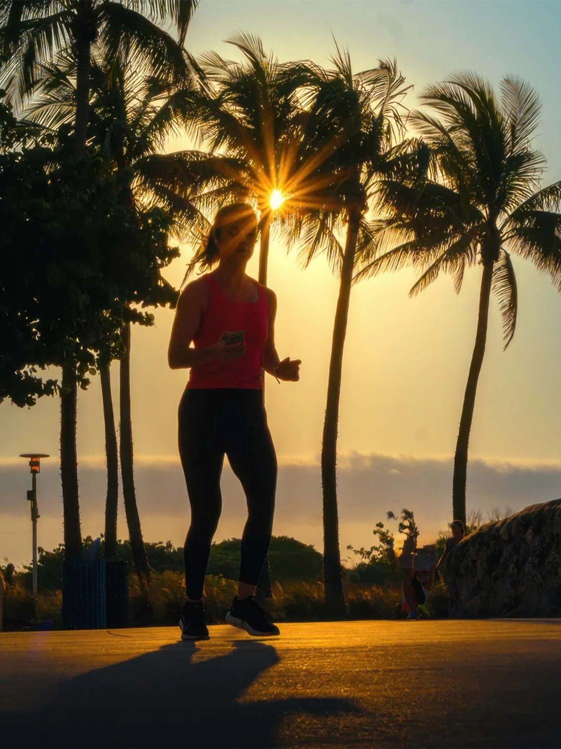 South Beach sunrise run woman jogging palm trees golden hour outdoor fitness workout tropical beach path.