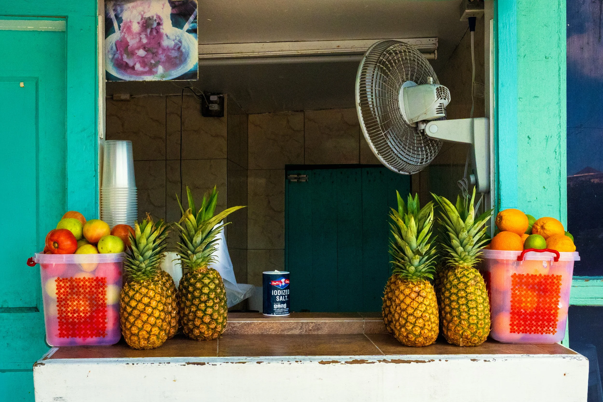 Fresh tropical pineapples and citrus fruit for sale at Arawak Cay Nassau Bahamas street food market stall.