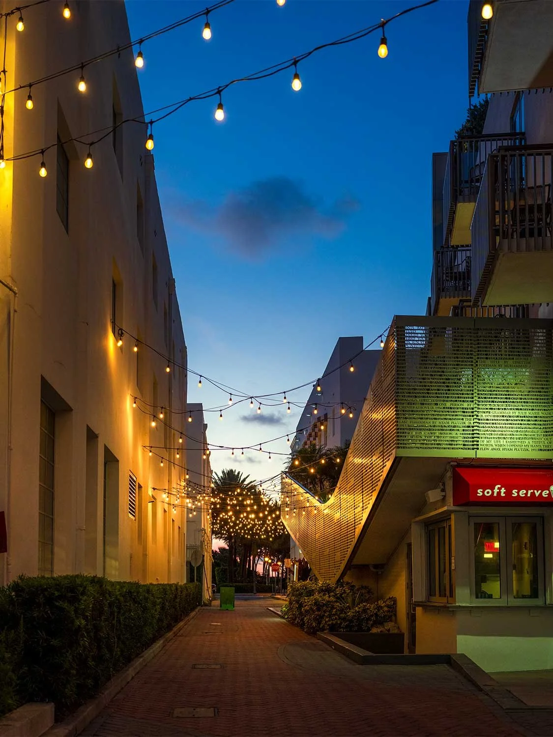 South Beach Miami alley at night with string lights, palm trees, and soft serve storefront at blue hour.