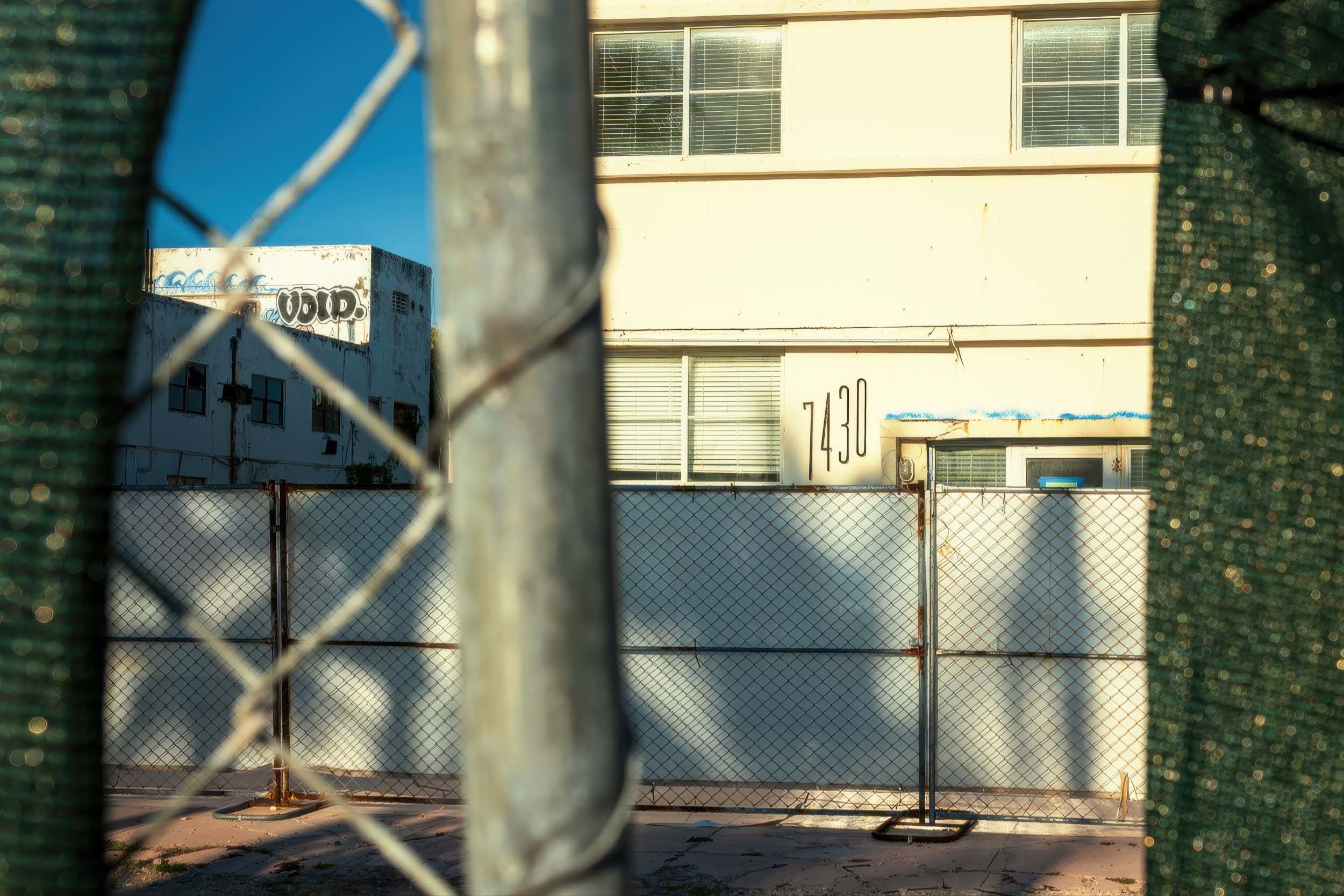 7430 Ocean Terrace hotel building seen through construction chain-link fence, North Beach Miami