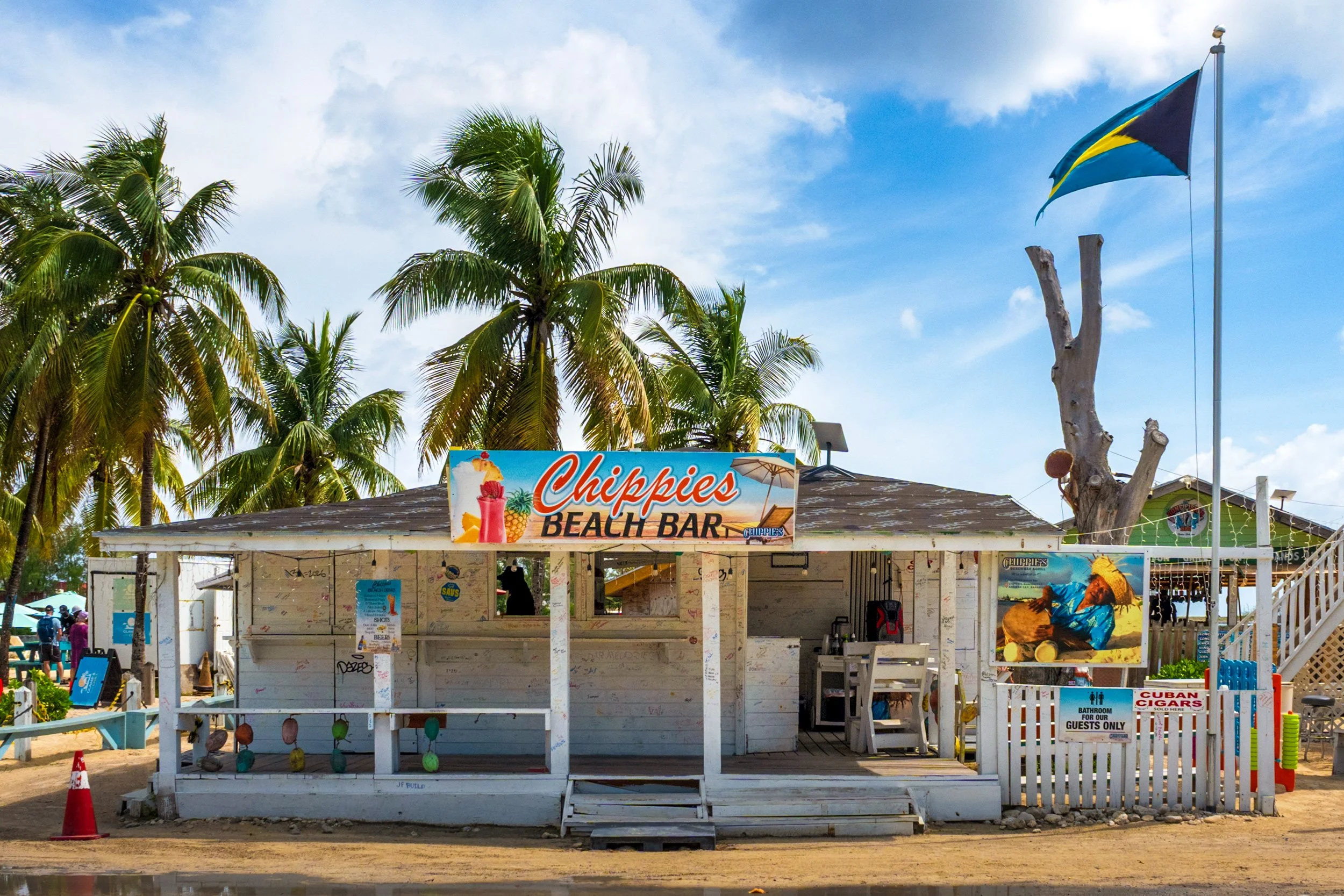 Chippies Beach Bar Nassau Bahamas at Arawak Cay, tropical outdoor bar with palm trees and Cuban cigars sign.