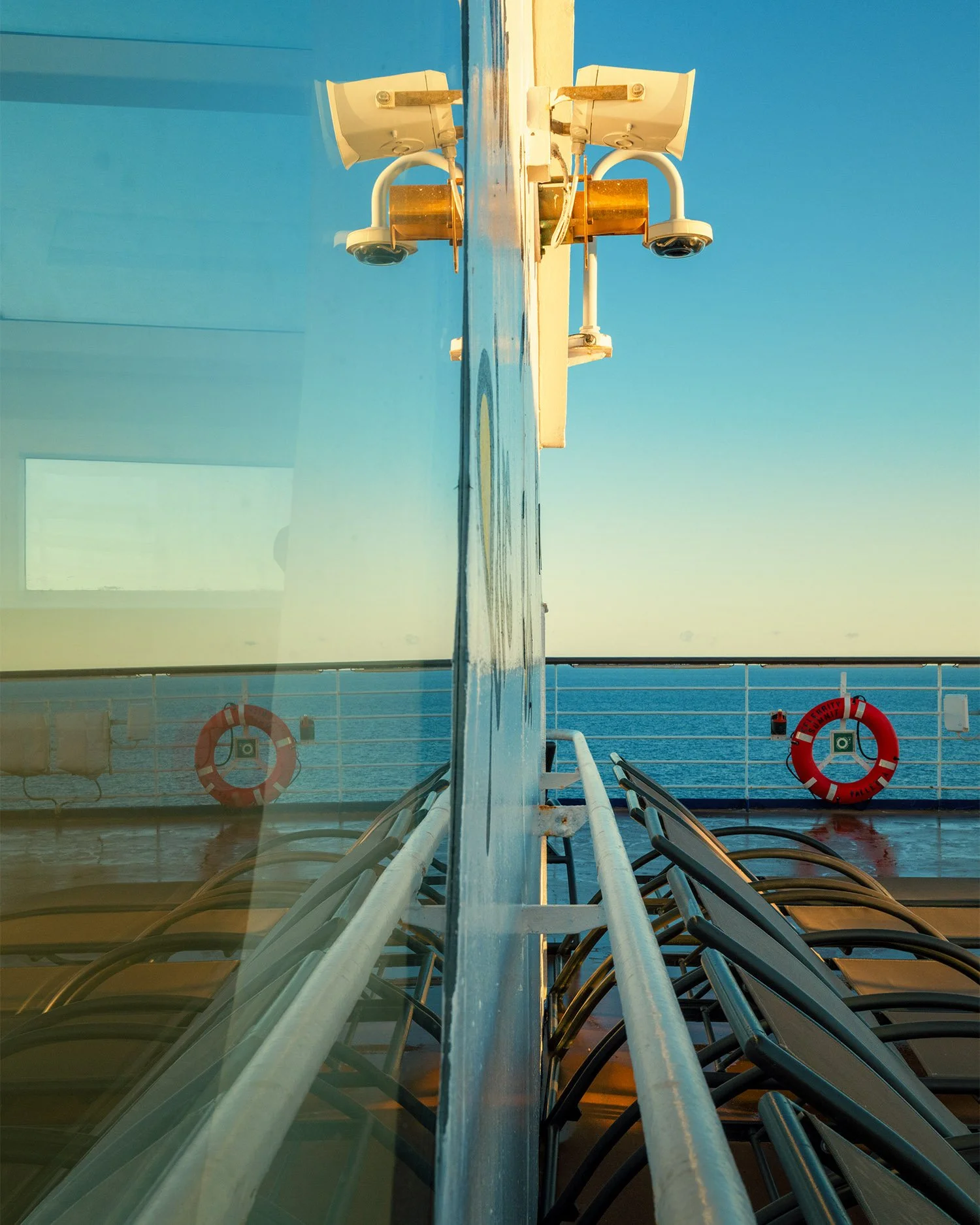 Reflection of a life ring through ship railing, wet deck