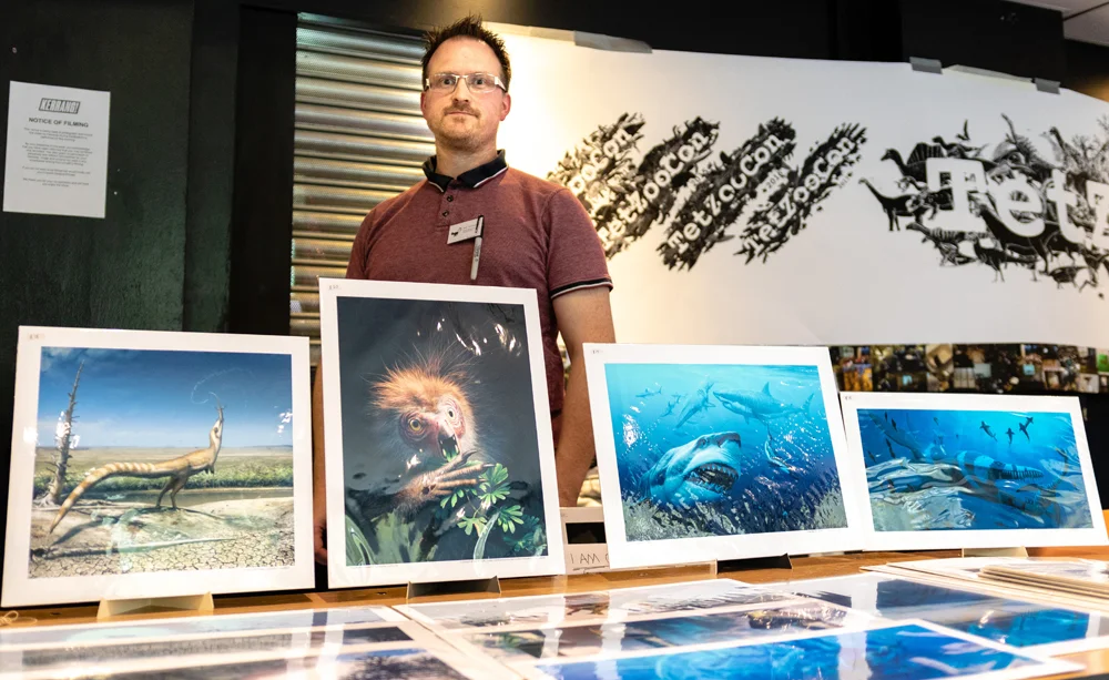 Bob Nicholls of Palaeocreations was selling prints, including those featuring the cover and concept art for Naish & Barrett’s Dinosaurs: How They Lived and Evolved . Image: Xane/Michael Lesniowski.