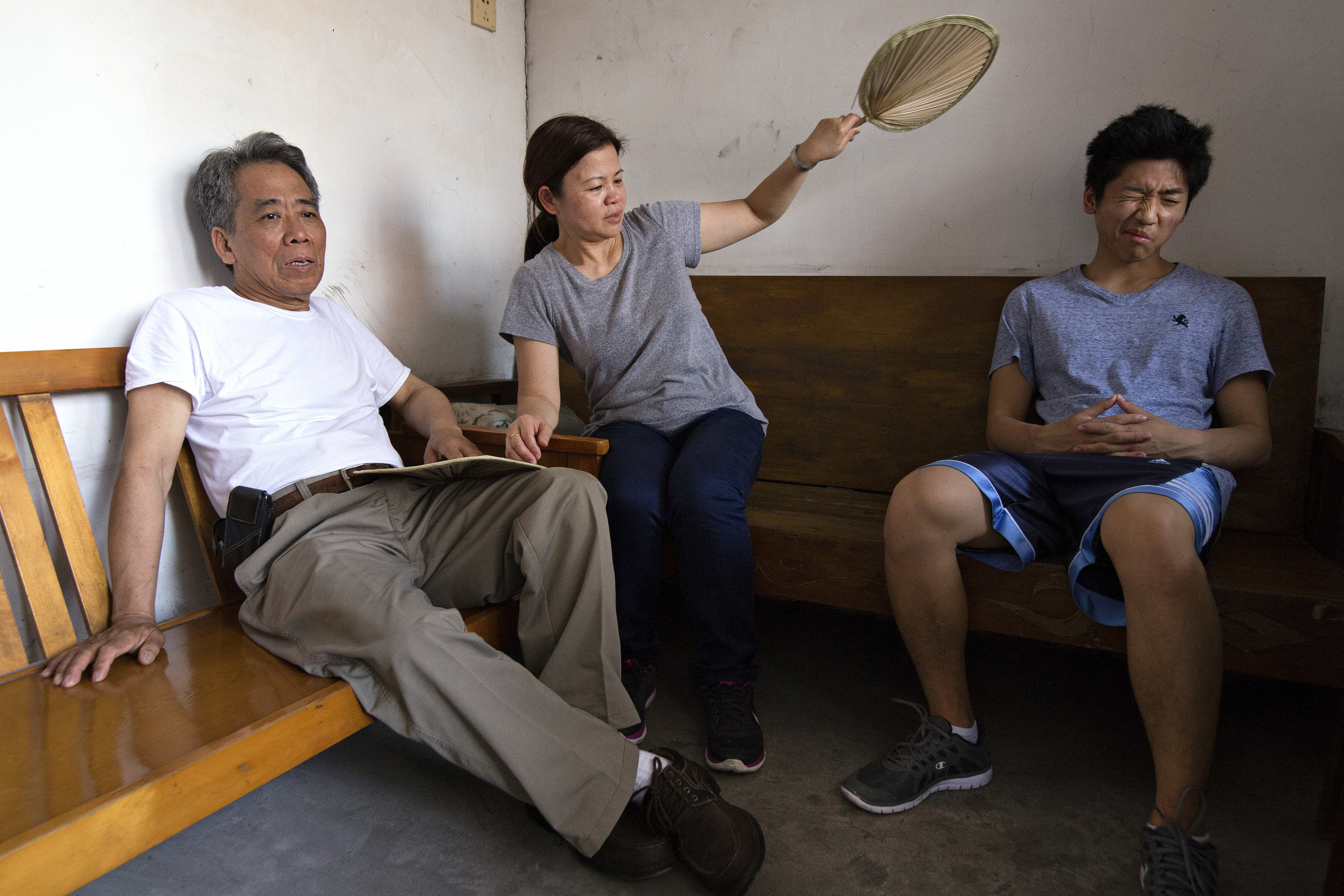  Father, mother and my brother, Ted, sit on wooden benches handcrafted by Gongong. “This was also Gonggong’s bed. This is where he slept,” Mother remarks, referring to the bench on the right.&nbsp; 