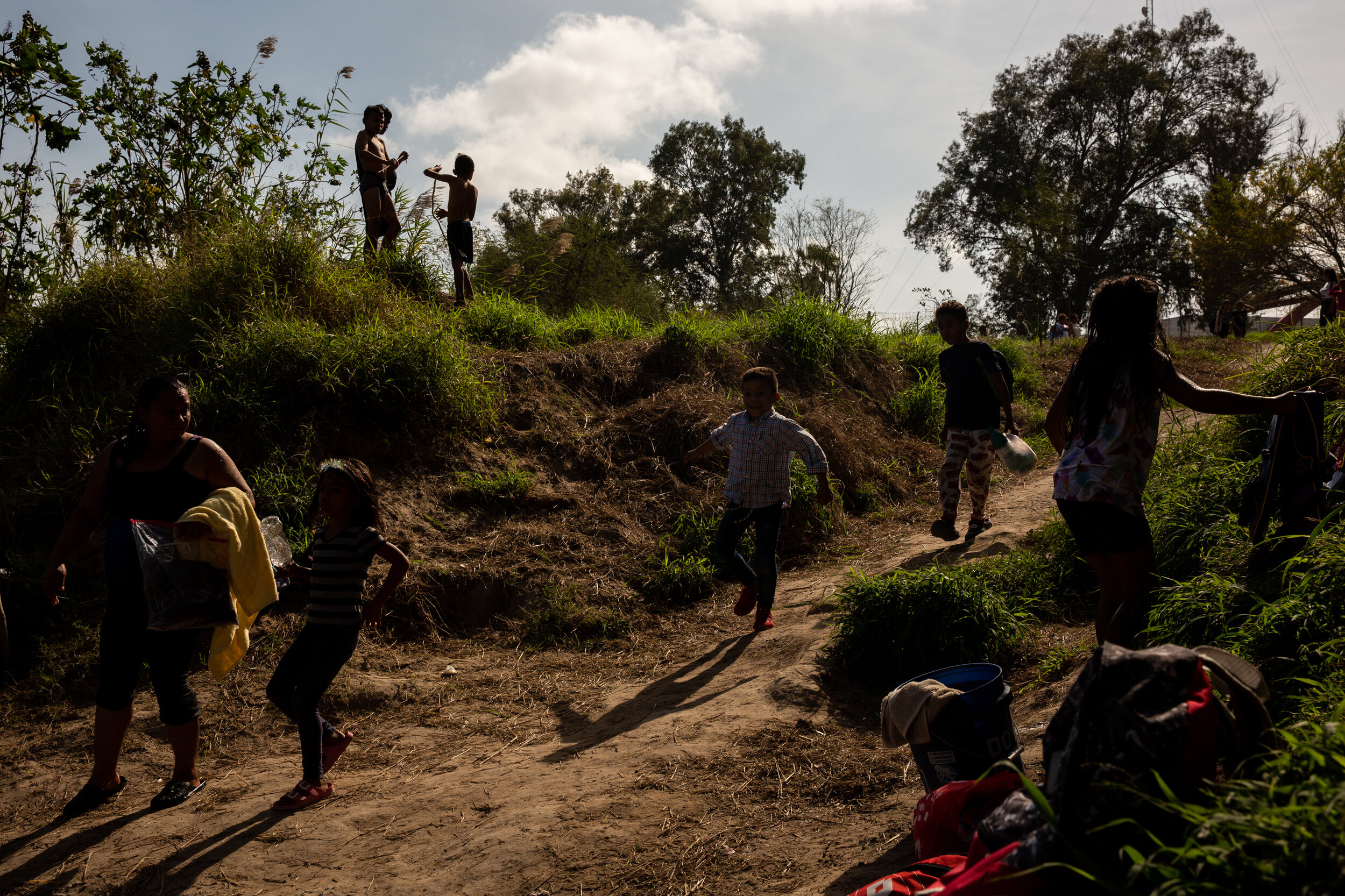  Children from the Matamoros migrant camp run down to the river bank where they prepare to take a swim in the Rio Grande.  