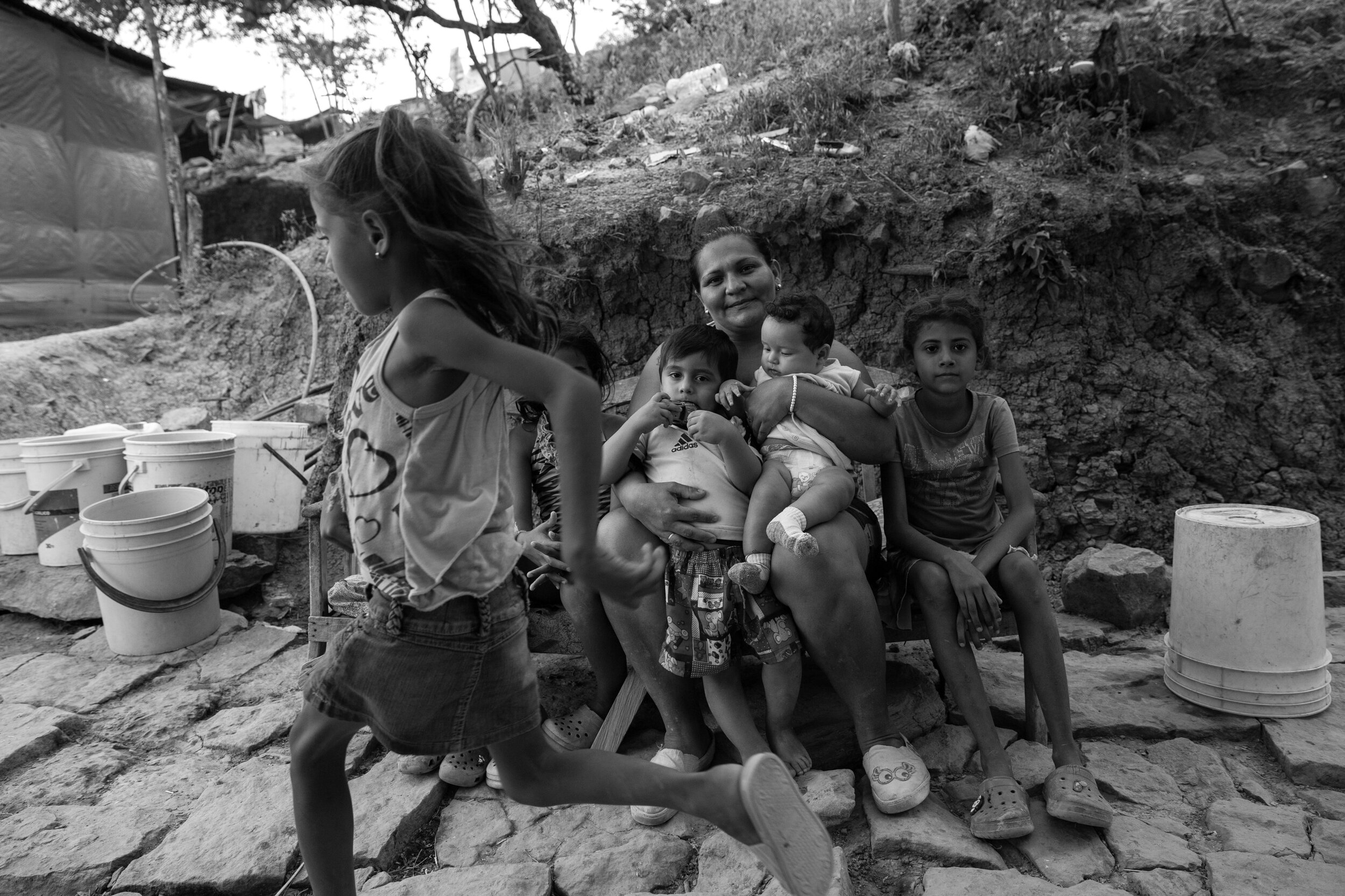  Yuri Castro, 32, sits with her children for a portrait outside their home. None of the children are enrolled in school. She remembers when she arrived nearly two years ago: “Those were the worst days of my life.”  She begged repeatedly for a plot in