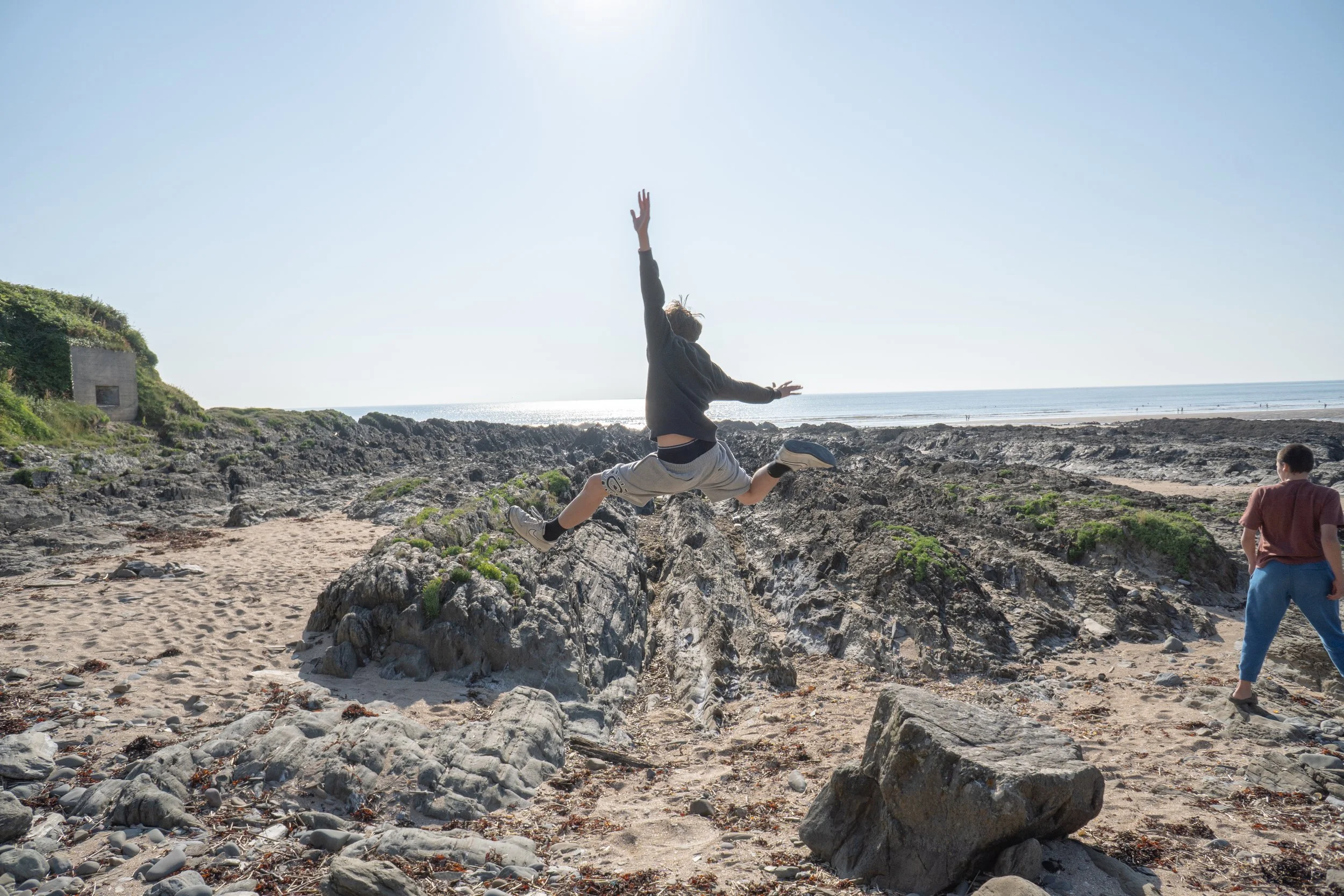 2025-06-18_boy-leaping-on-rocky-beach.jpg
