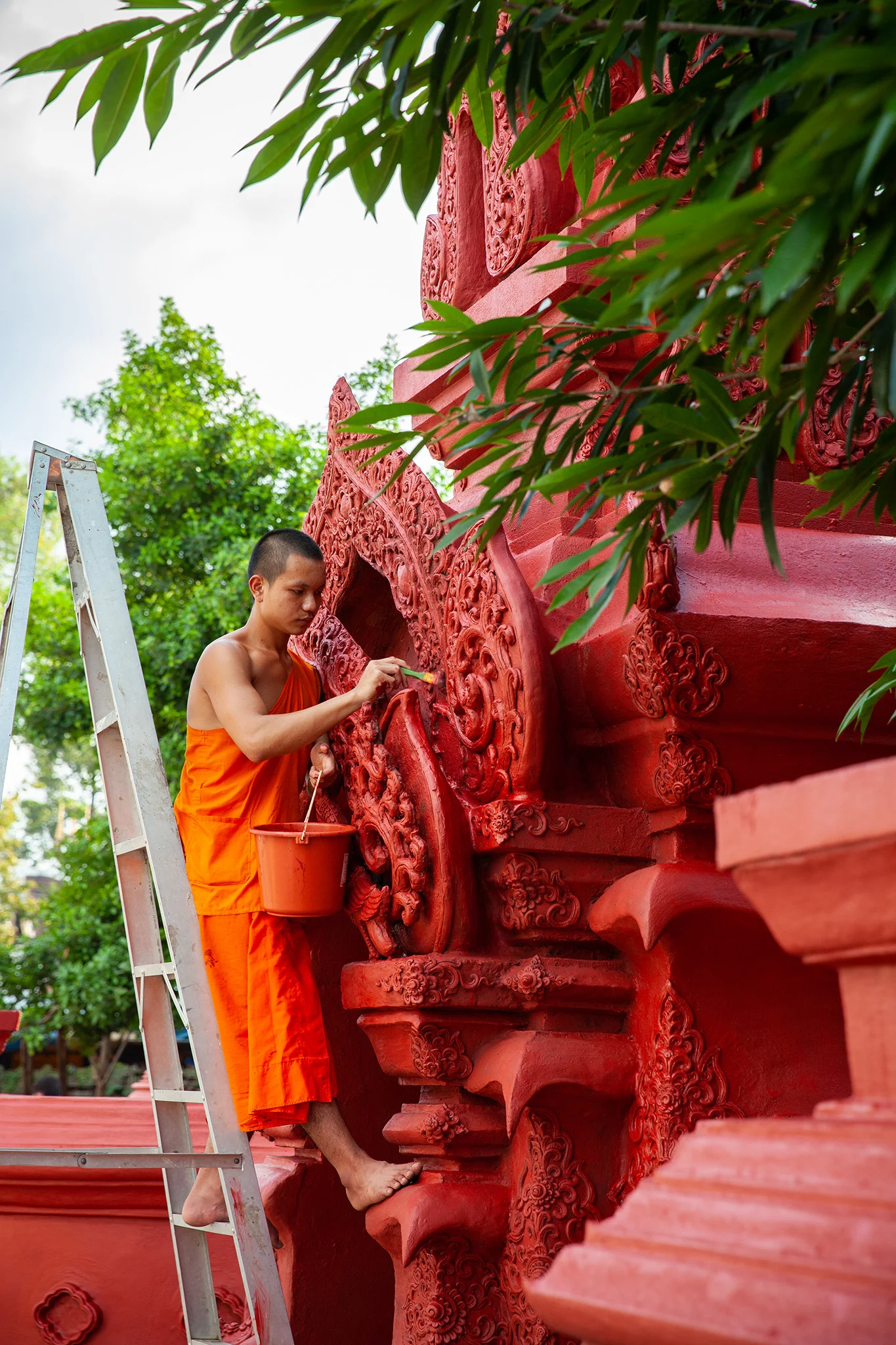 a young monk touches up the paint at Wat Chedi Luang