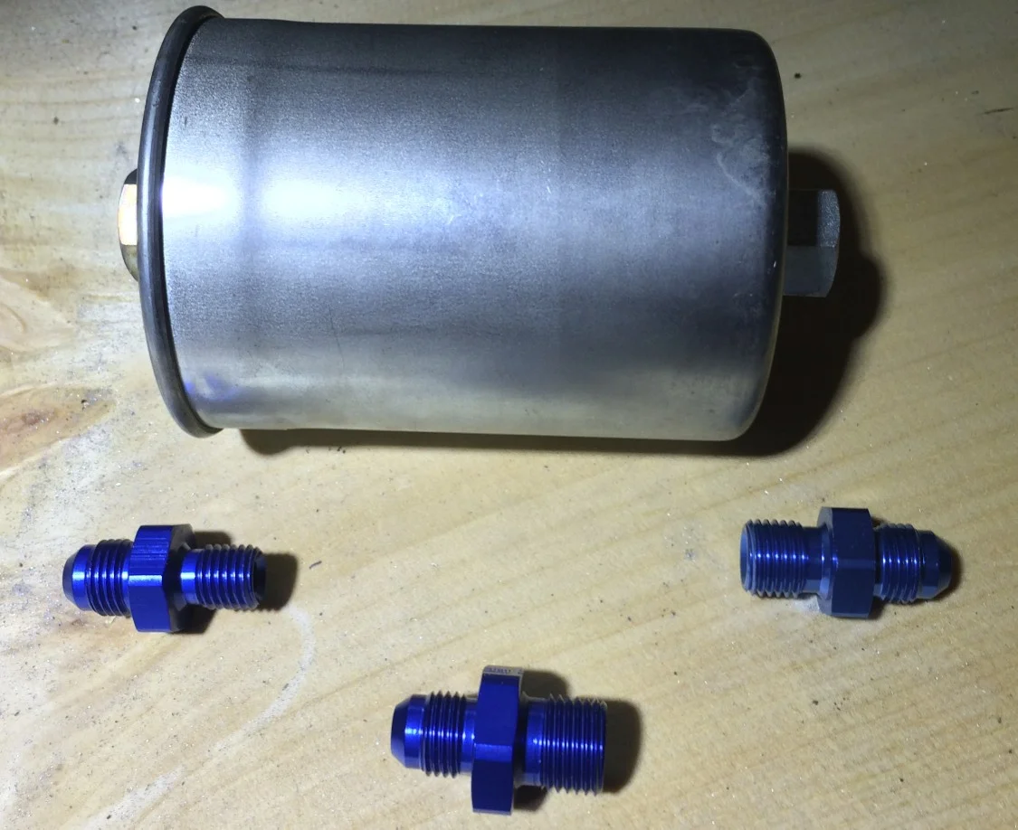 The fuel filter and adaptors. The smaller adaptor (left) goes into the top of the fuel filter (top), while the medium sized one (right) goes into the bottom. The largest one (bottom) connects to the hard line near the frame..\
