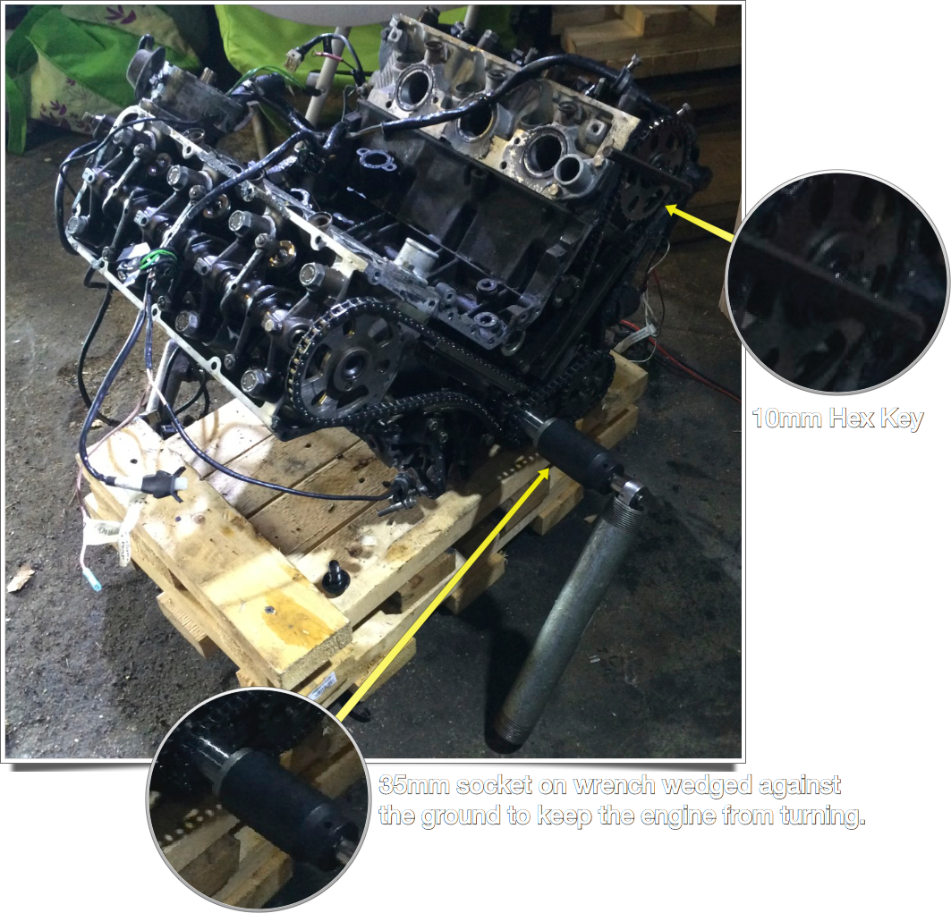 Removing the timing sprockets with a 10mm hex key. To keep the engine from turning, a 35mm socket was used to tighten the main pulley nut a bit, and the wrench wedged against the ground.