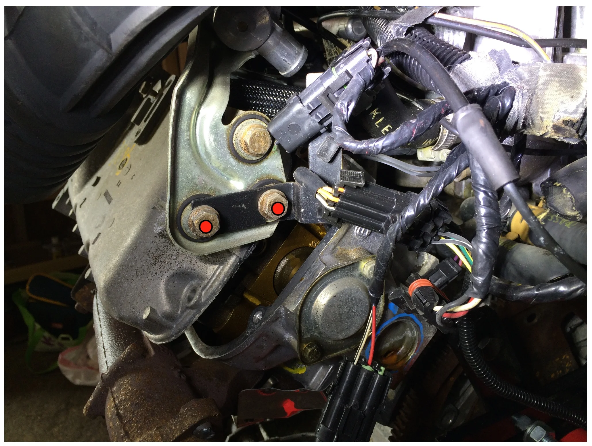 The cold air temperature sensor is mounted on the back of the head, and can be removed by taking out the two nuts marked in red with a 13mm socket. I had already taking out the valve cover heads before realizing the harness was there. 