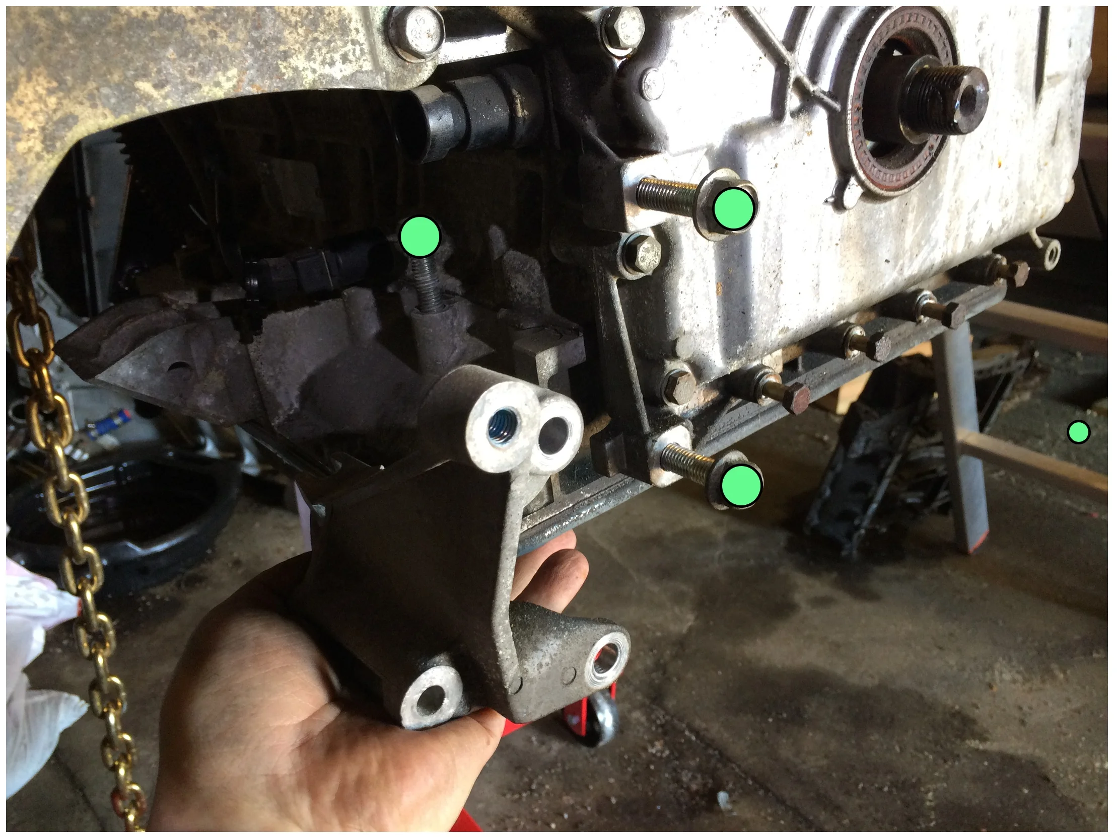 Three bolts (green, 15mm socket) hold a bracket to the bottom of the engine.