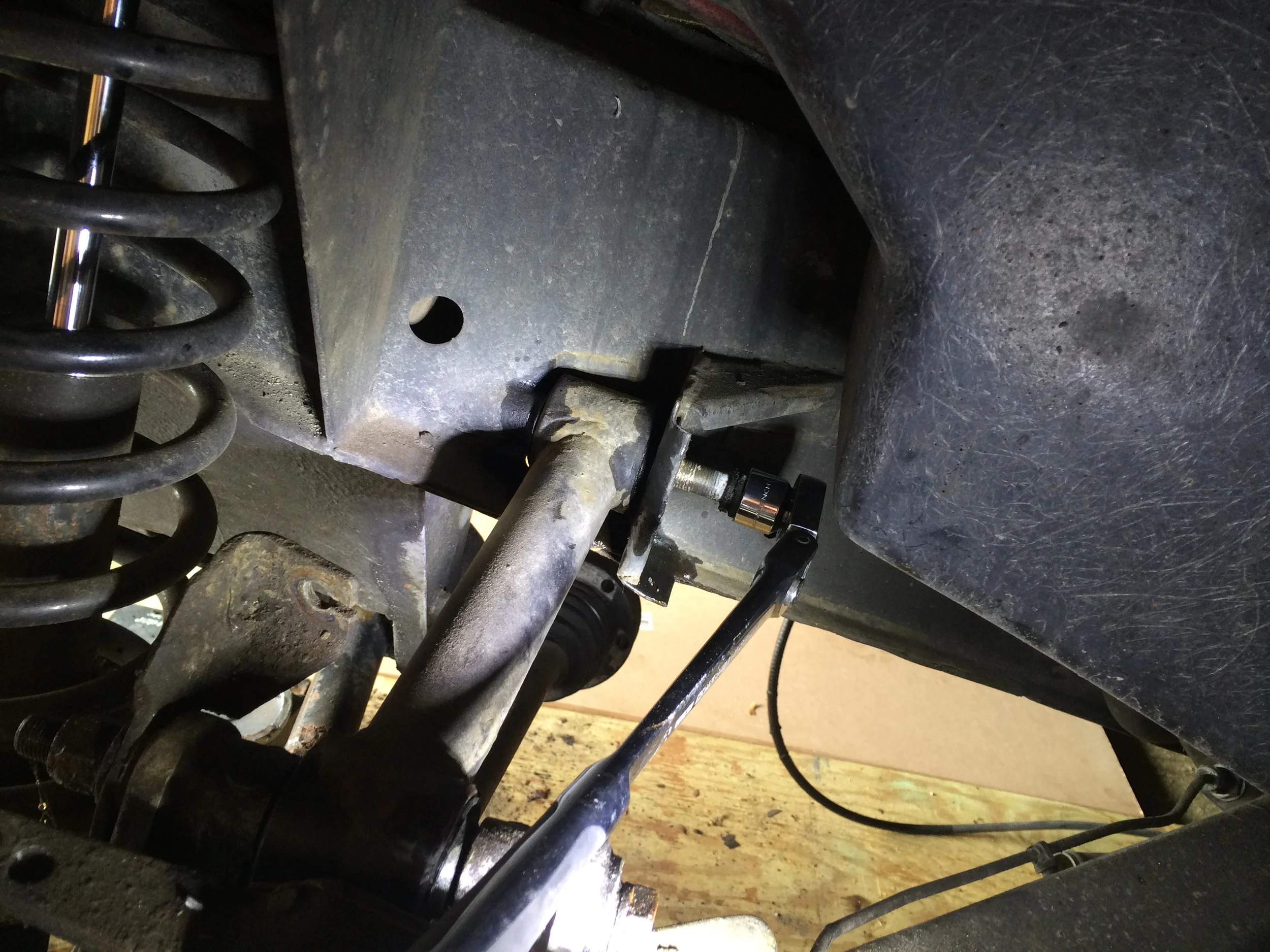 Using a wrench to remove the bolt securing the lower link arm to the frame.