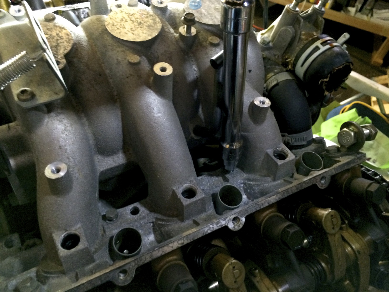 Removing the intake manifold's bolts with an 11mm socket.