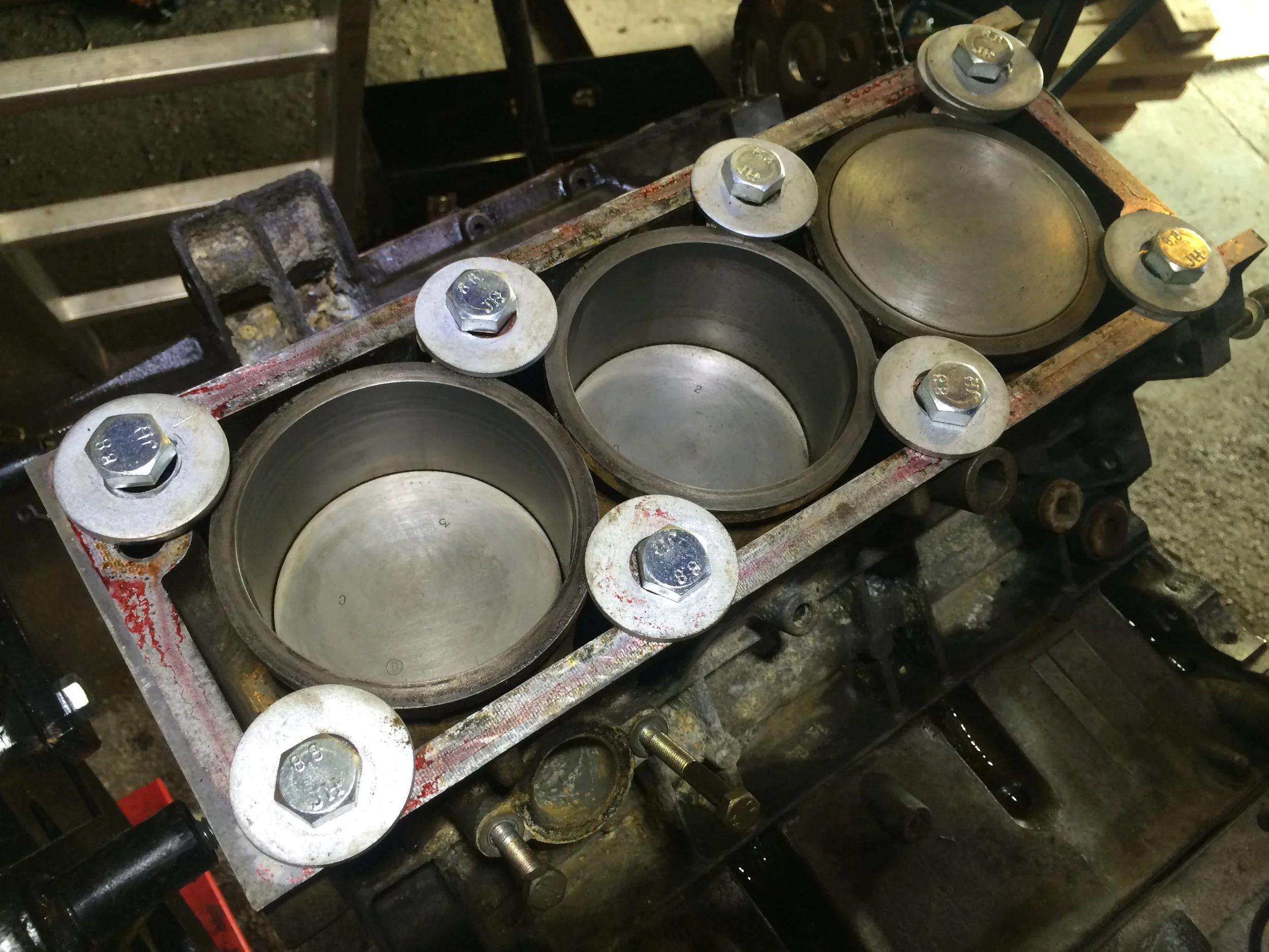 The cleaned pistons and liners. The red visible around the block is spray-on high-tack sealant; I had already assembled the heads when I'd realized I should clean then, and had to remove them. The sealant is optional, and easily cleans up with brake cleaner.