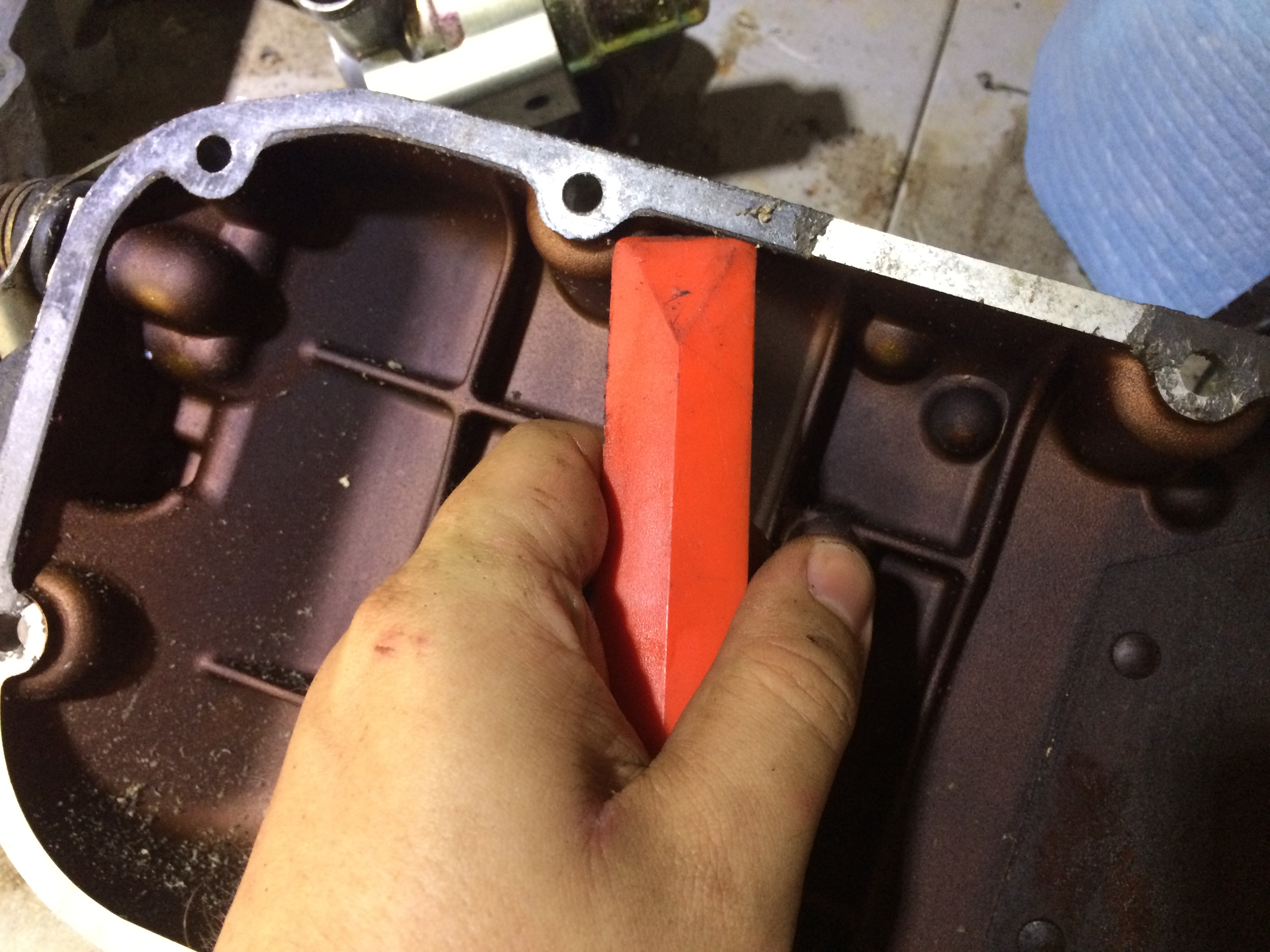 Prying up the old gasket with a plastic scraper.