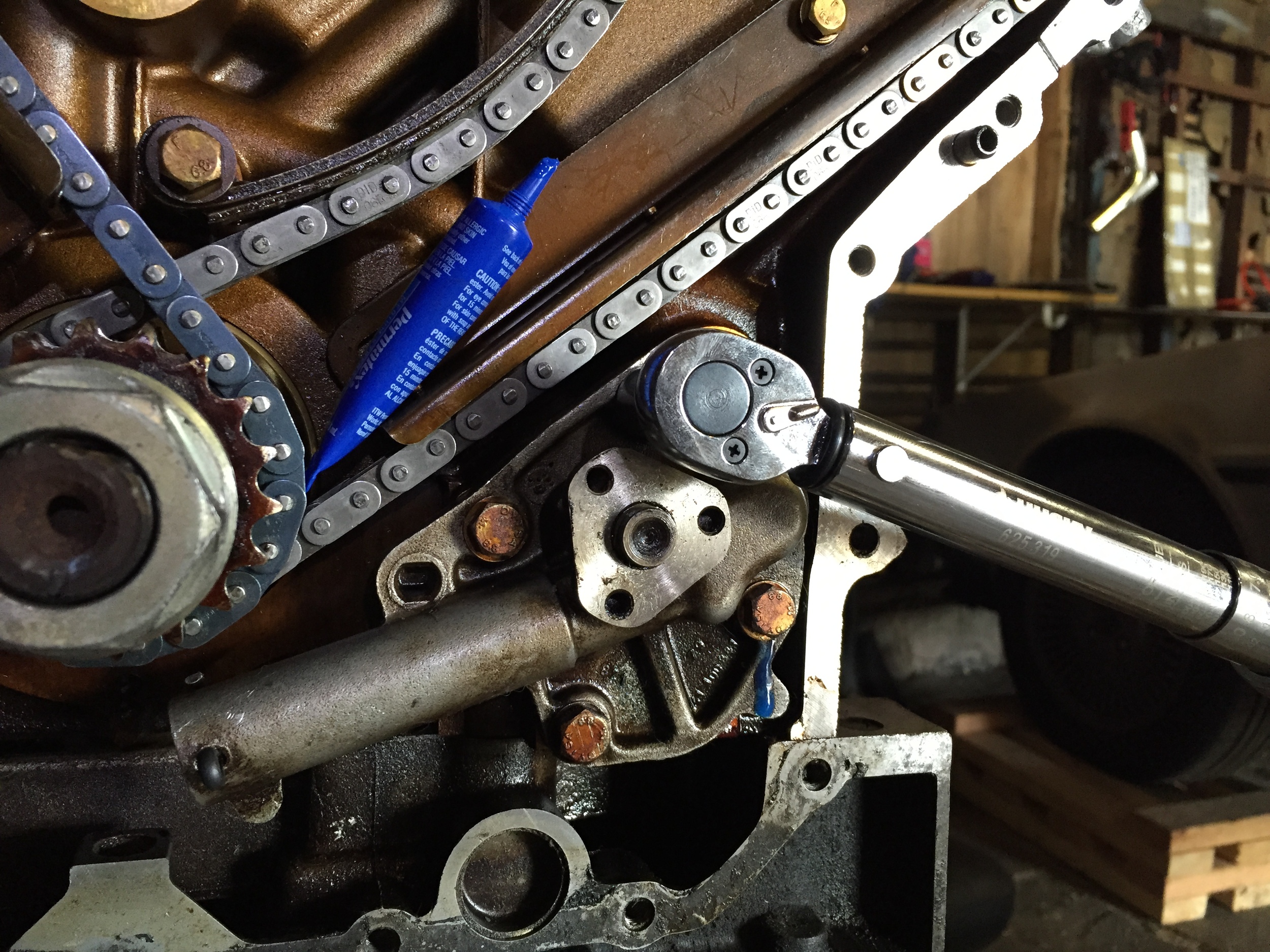 Torquing down the oil pump. The tube of blue LockTite can be seen resting on the chain guide,