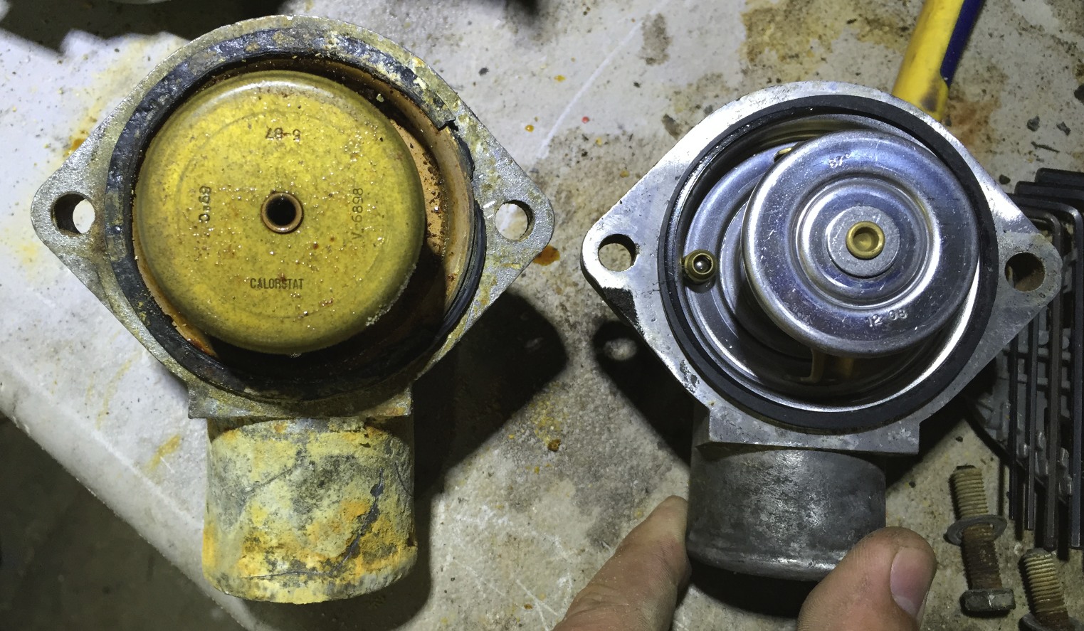 The extremely dirty 3.0L thermostat and housing (left) and the clean 2.8L thermostat (right).