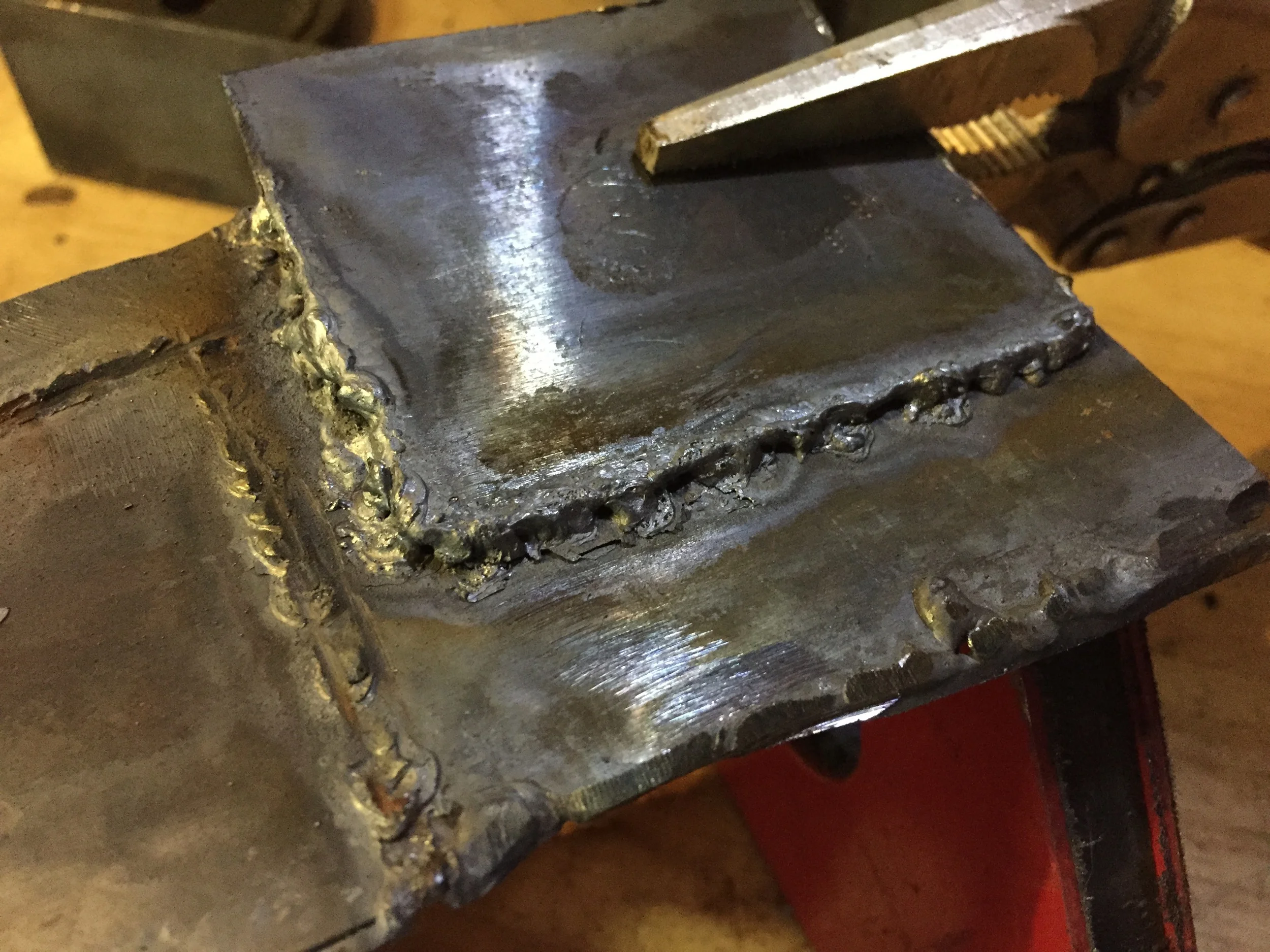 An absolutely worthless "weld". This one was easily pulled apart with my hands as though the two pieces of metal were held together with tape. Everything about this weld is bad. Really, only the top piece of metal melted; the bottom had glowed under the heat, but really hadn't bonded, most likely because it was dirty from previous practice welds.