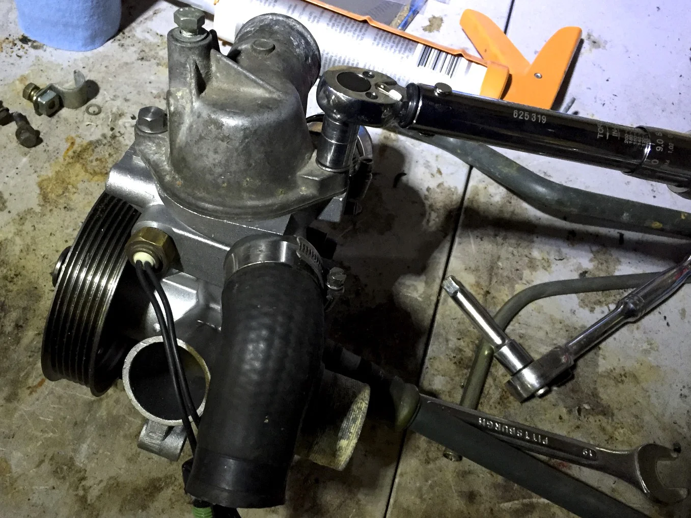 The thermostat housing's bolts being torqued to 9 ft lbs. with an 11mm socket.