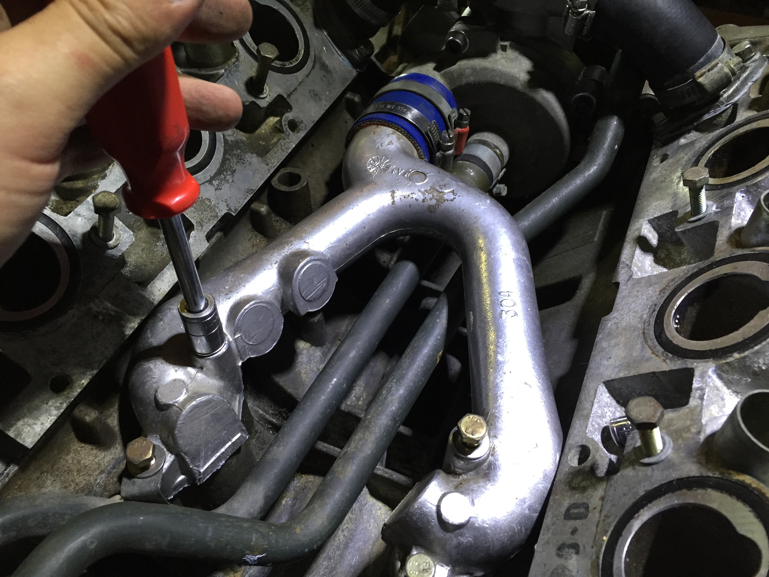 Installing one of the four bolts that hold the "Y" pipe in place with an 11mm socket on a bit driver.