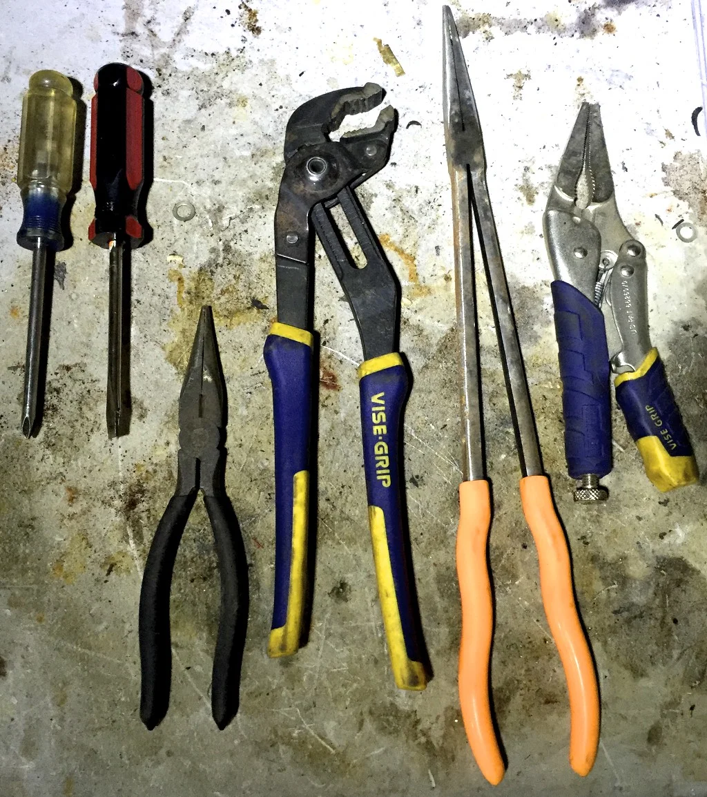 From left to right, Philips and flathead screwdrivers, pliers, adjustable pliers, long-handled needle nose pliers, locking pliers (aka vice grips).