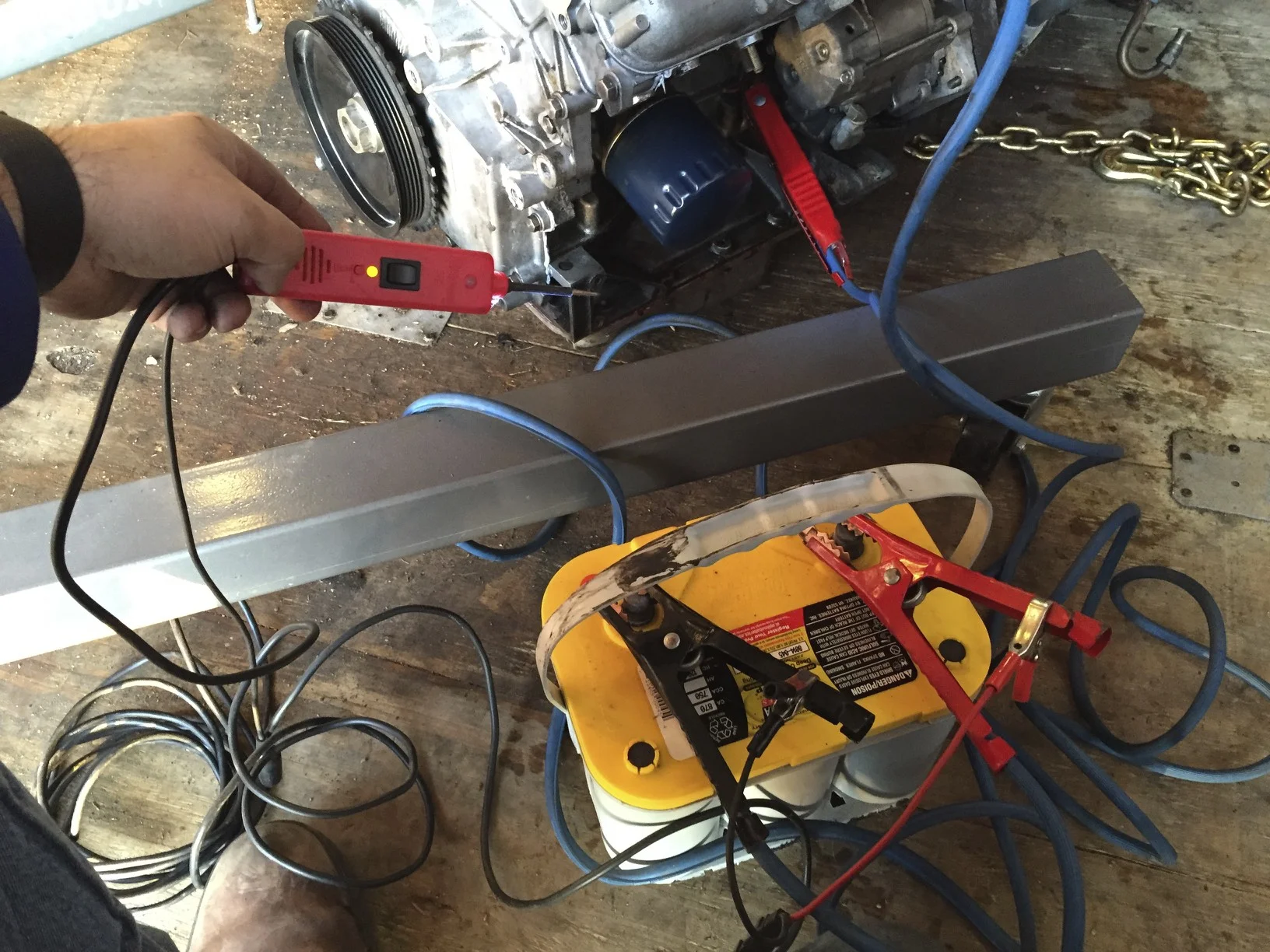 The car battery's is connected to the engine with jumper cables, with ground running to the block and positive carefully attached to the post on the starter. A wire running from the starter solenoid is energized with a PowerProbe.