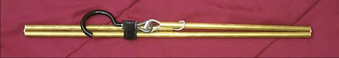 Coat hanger collapsed. A piece of velcro atteched to the hook keeps the pieces together. The rubber-coated hook and layered brass tubes do not clank together when moving. There is no need to disassemble the hanger to collapse it.