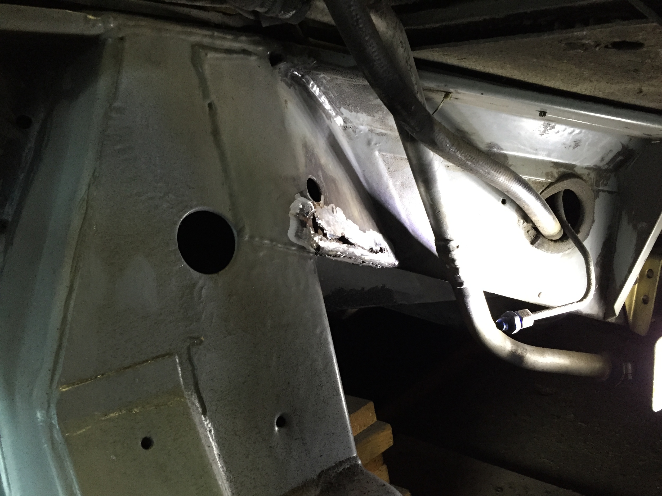 The new hole found above the one on the driver's side, after being cleaned up with an angle grinder.