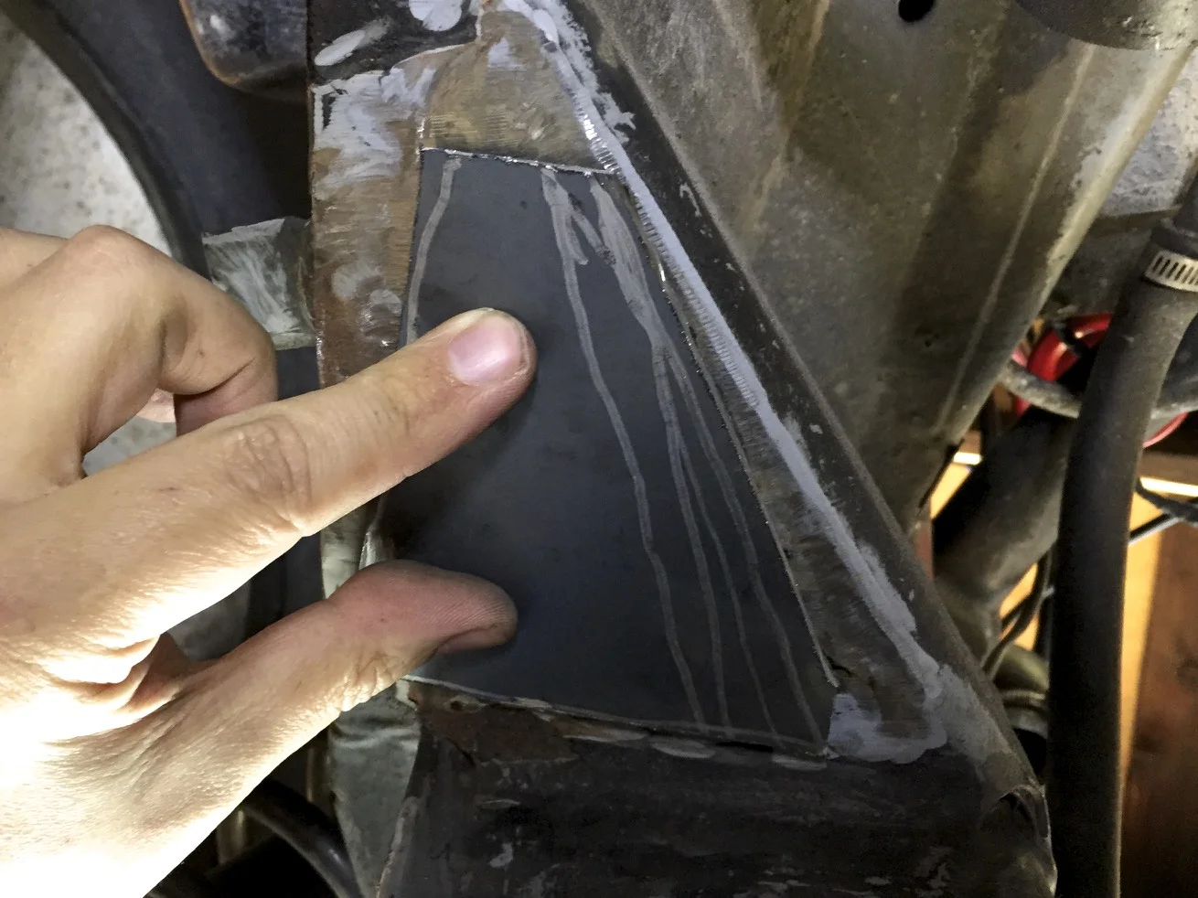 The new patch cut to size and test fit, after grinding away the epoxy and rust around the hole.