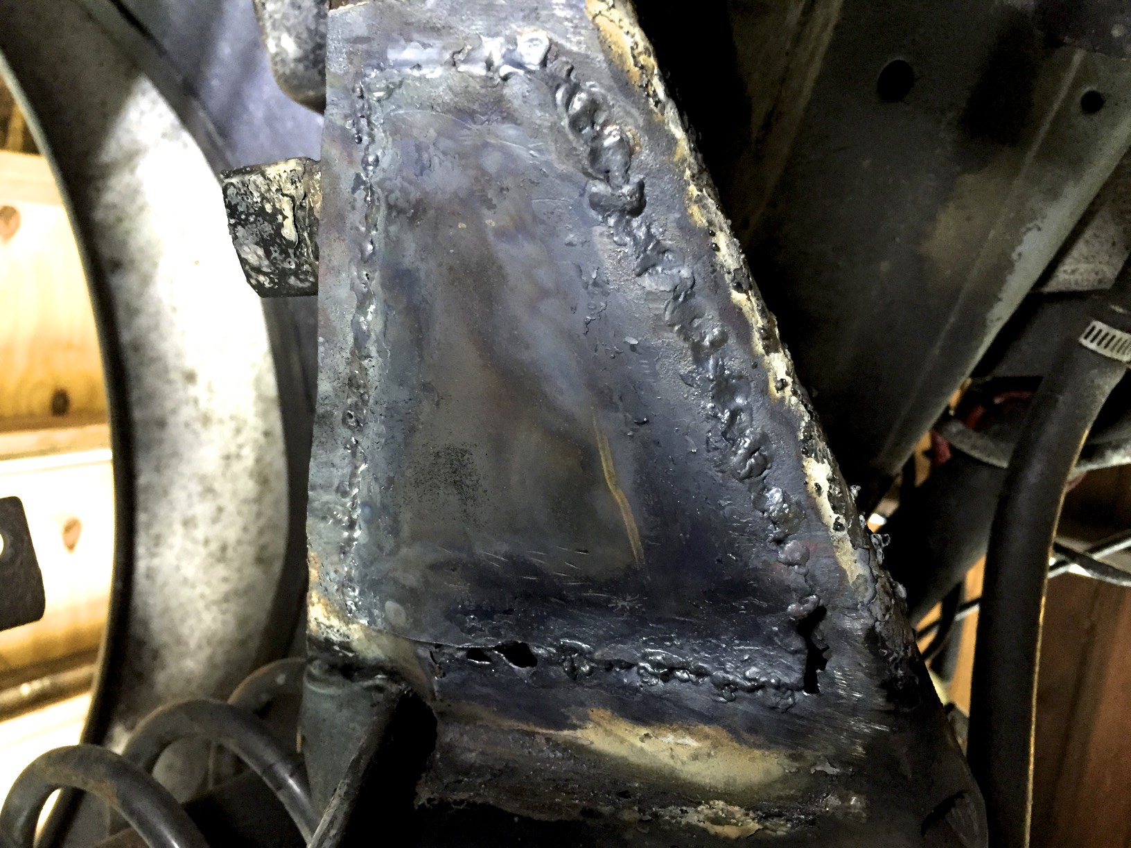 After grinding down the right side of the patch, I reworded it with better results. Unfortunately, my attempts at welding the bottom edge caused a few burnt throughs, and I decided to cover it with a second patch.