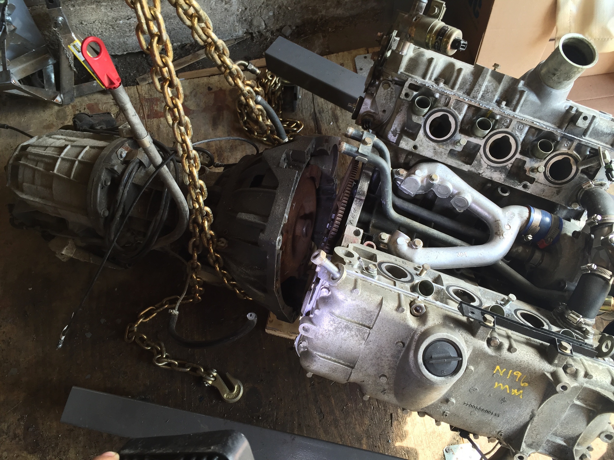Hoisting the transmission and propping it up with a block of wood so that it will align with the engine.