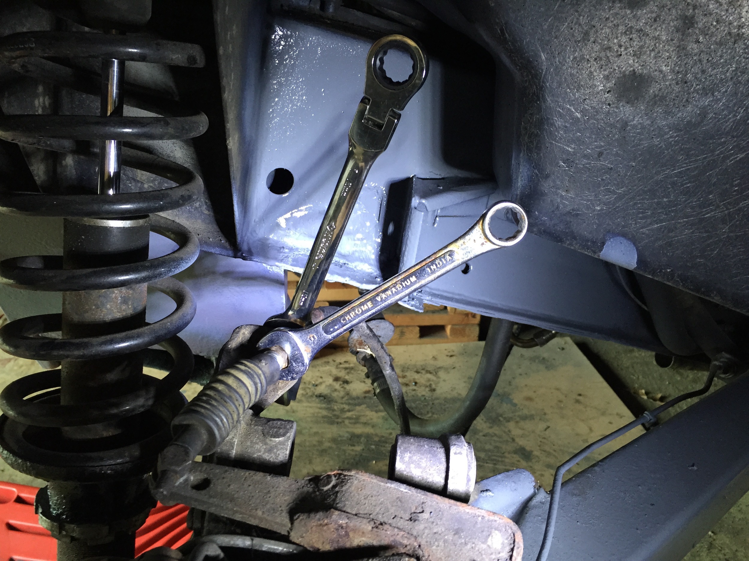 Two 15mm wrenches are used to tighten the cable against bracket. The brake is adjusted by changing the position of the nuts along the threaded rod through which the cable runs.