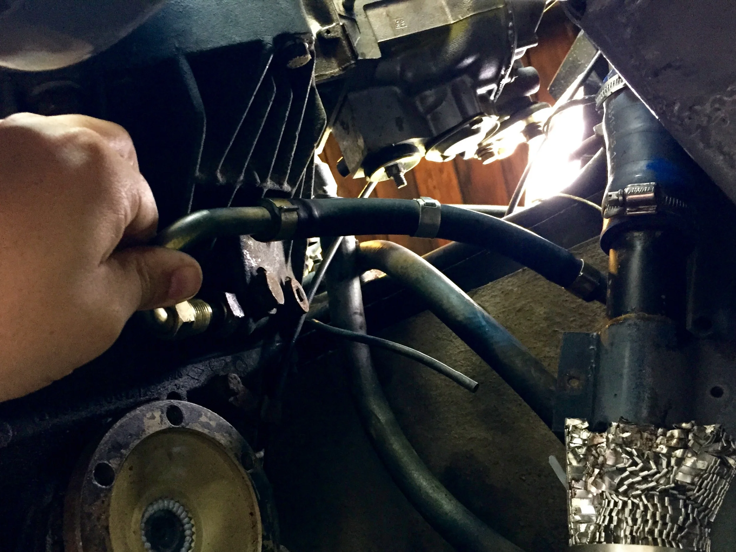 Flexing the cooler line to reach the hole. The strong rubber hose made this a little tricky, but I'm assured that this is correct.