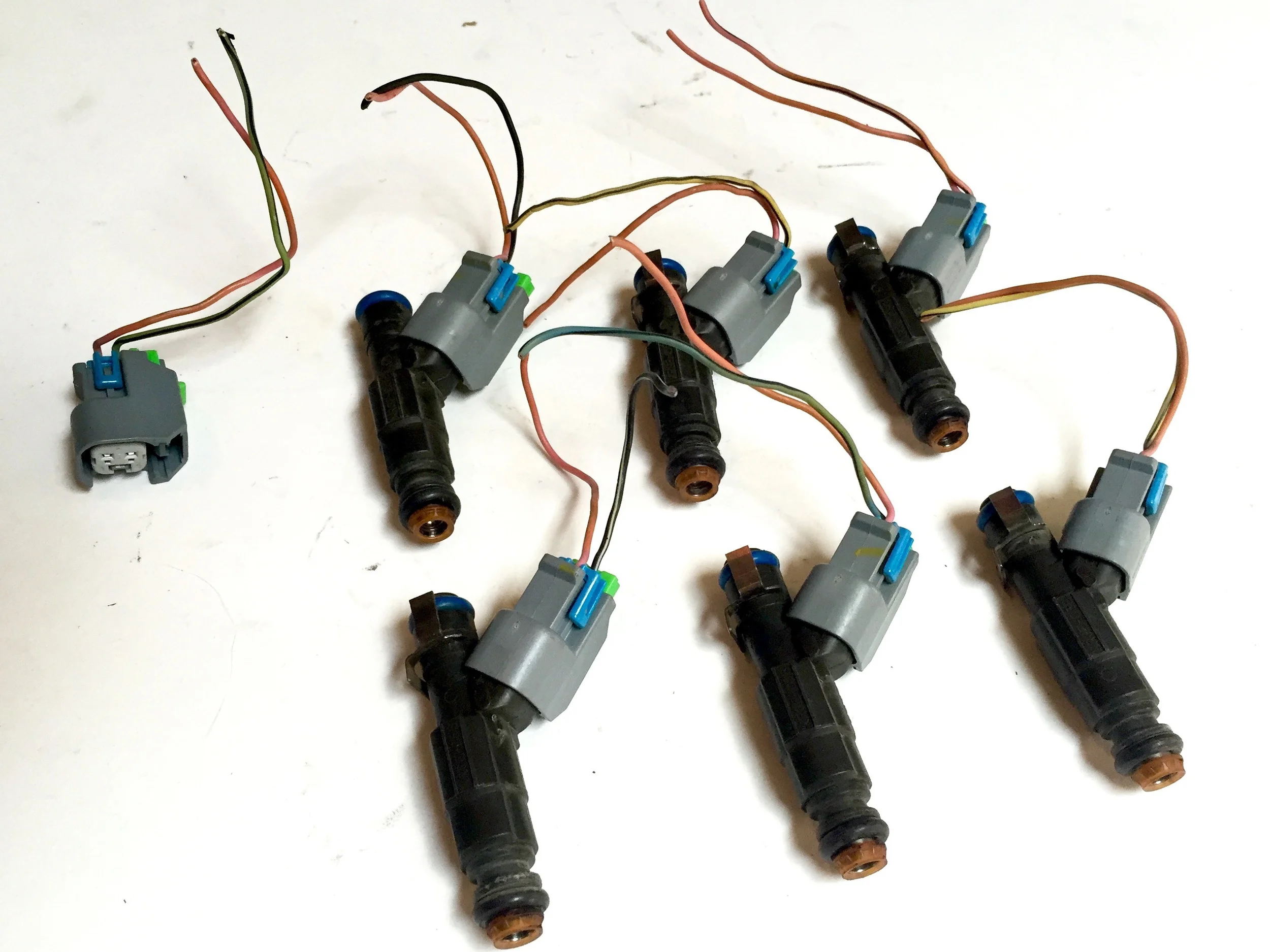 Six fuel injectors with their connector pigtails, plus a seventh spare connector.