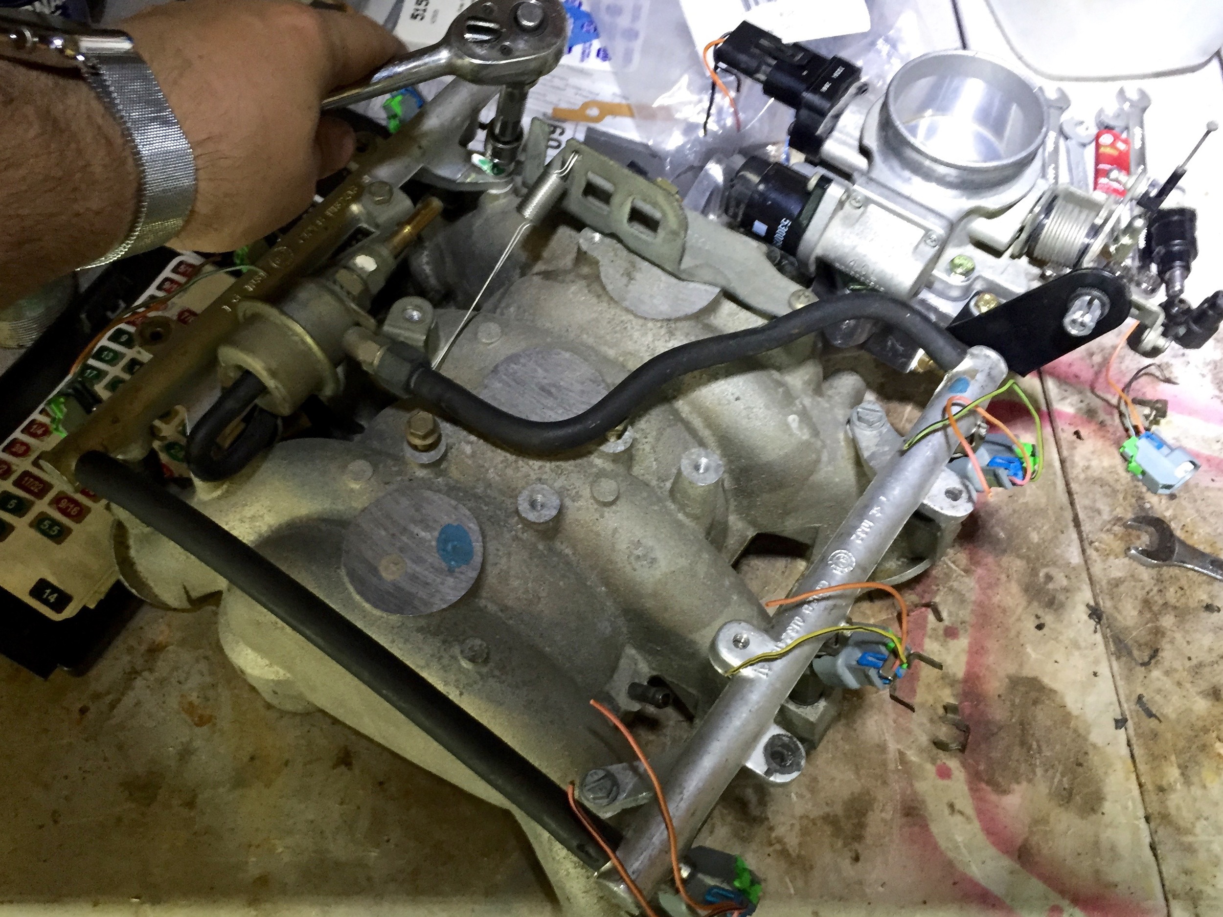 Tightening the fuel rail onto the intake manifold. The fuel pressure regulator is the cylinder next to the fuel rail on the left with the rubber lines connected to it..