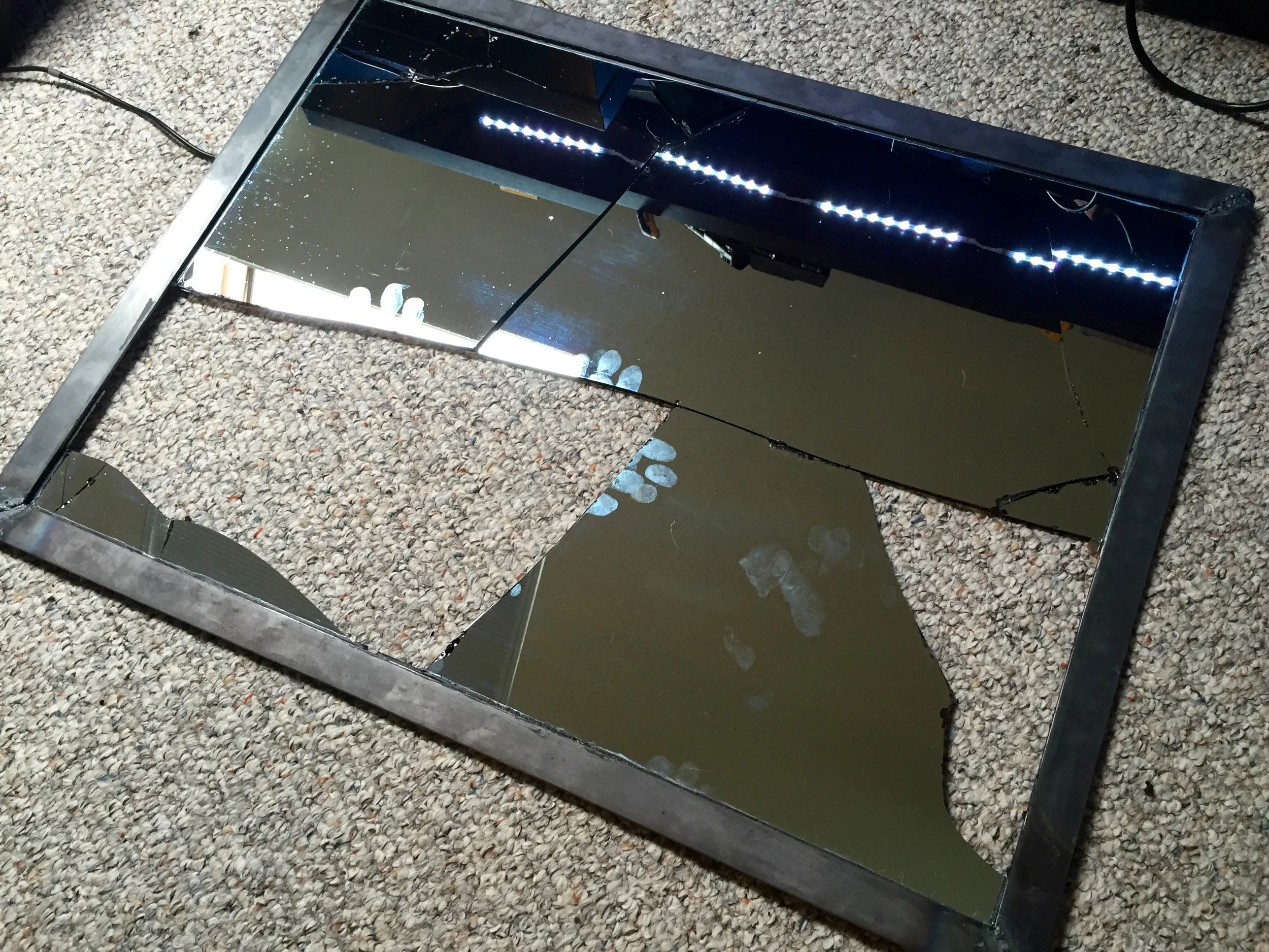 The old shattered mirror glass still attached to the metal frame.