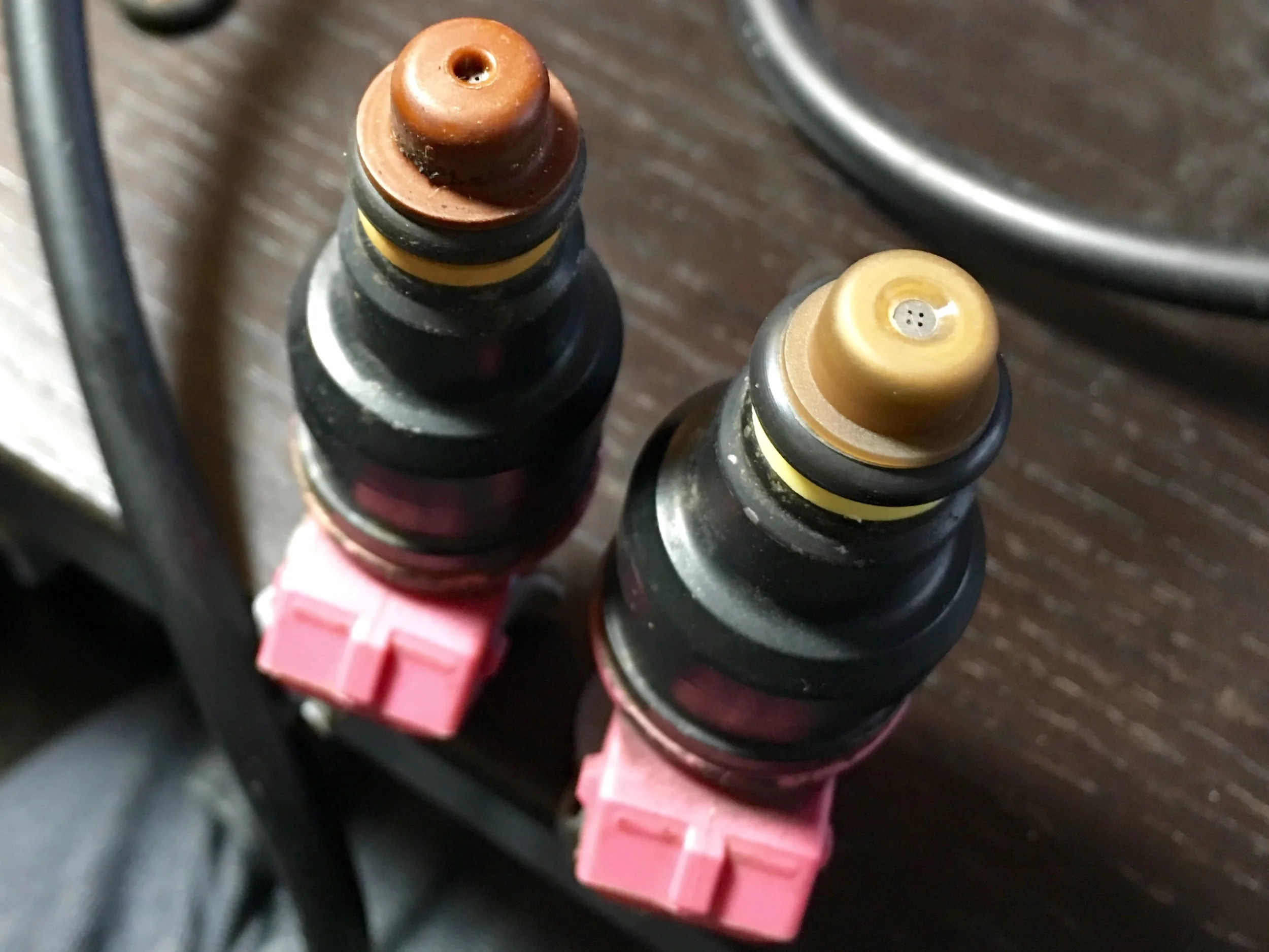 An injector with an old cap (left) and a new, noticeably more flush cap (right).