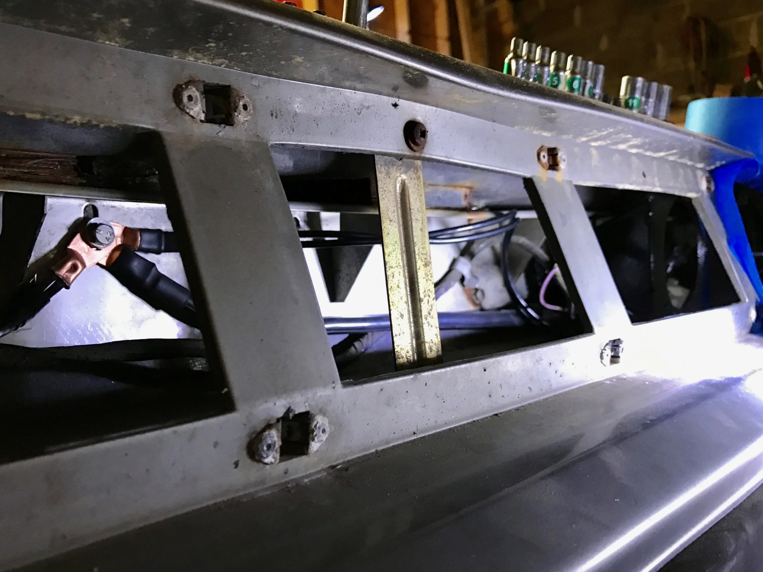The buss attached to the headlights. The copper terminals on the left the image are attached to the stainless steel plate behind the fascia. The middle wire is soldered to the bus wire, which runs to the driver's side corner past the washer bottle. The other two terminals are each crimped to a pair of wires, the other ends of which are soldered to the black wire bundles behind each pair of headlights.