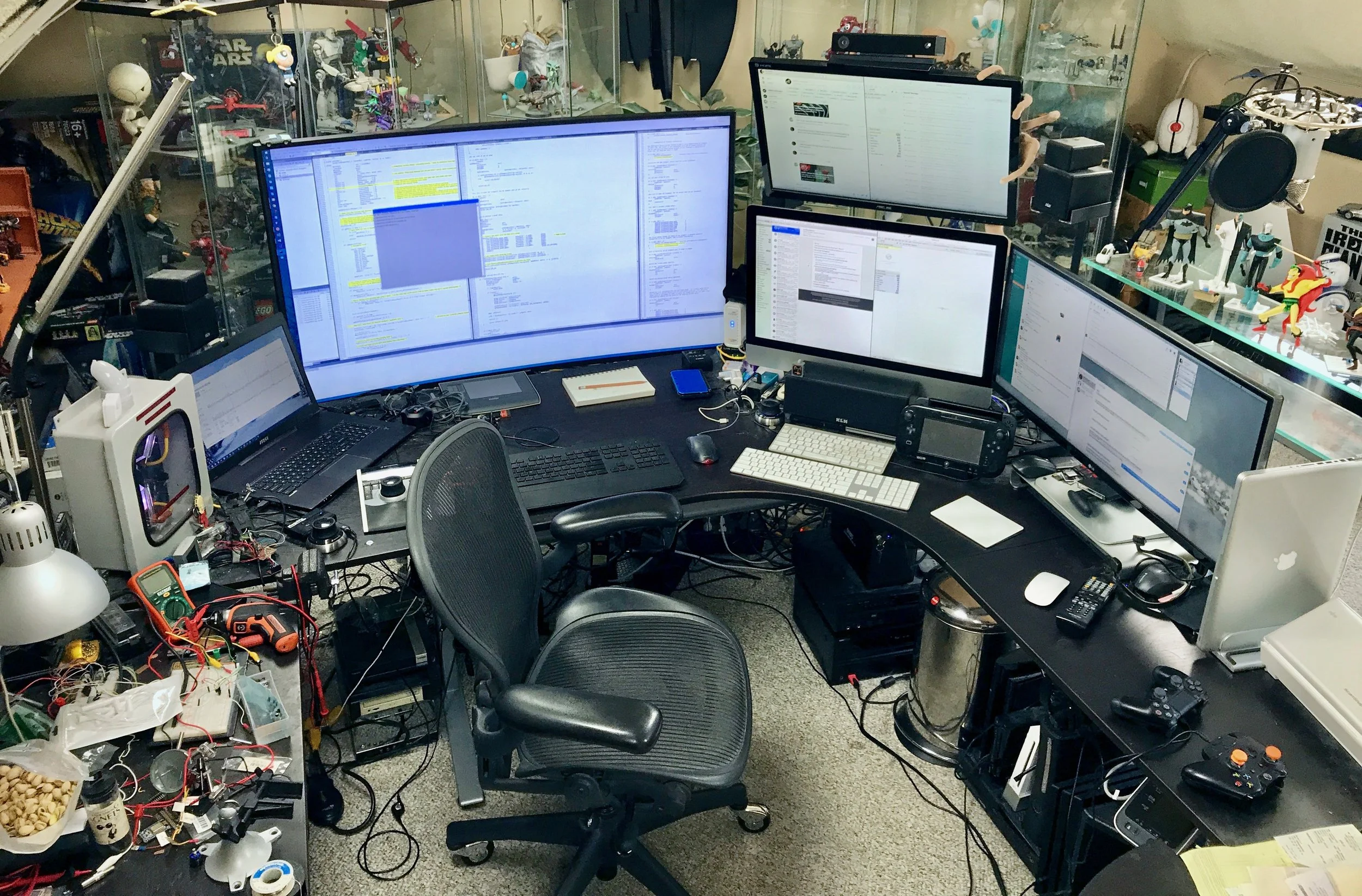 From left to right: MSI laptop, 55" curved TV, Mac mini monitor (top; the Mac mini itself is under the desk), iMac (bottom), LG Ultrawide, MacBook Pro. 