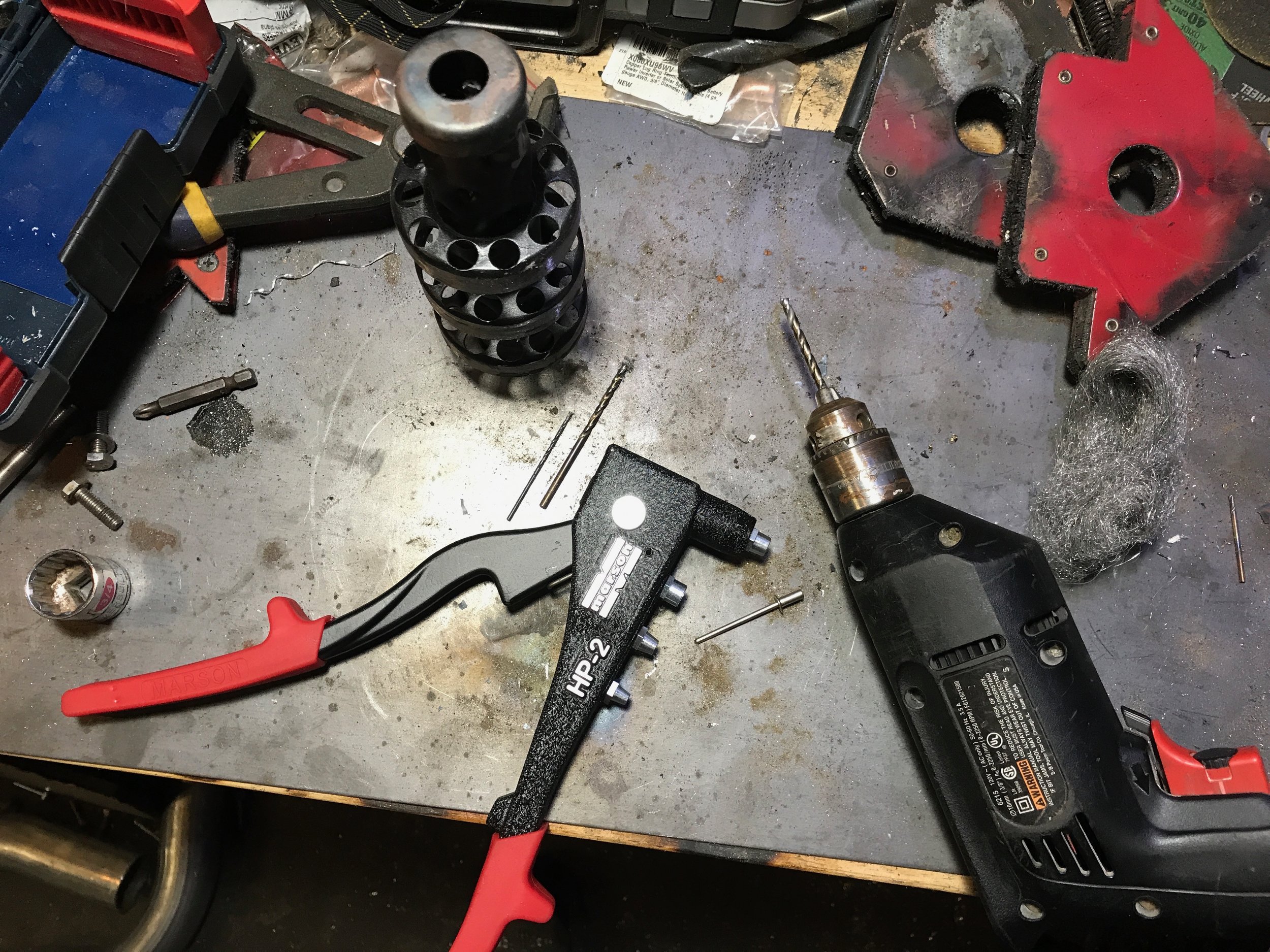 Tools for installing the silencer: a hand rivet tool, and a drill with various sized bits.