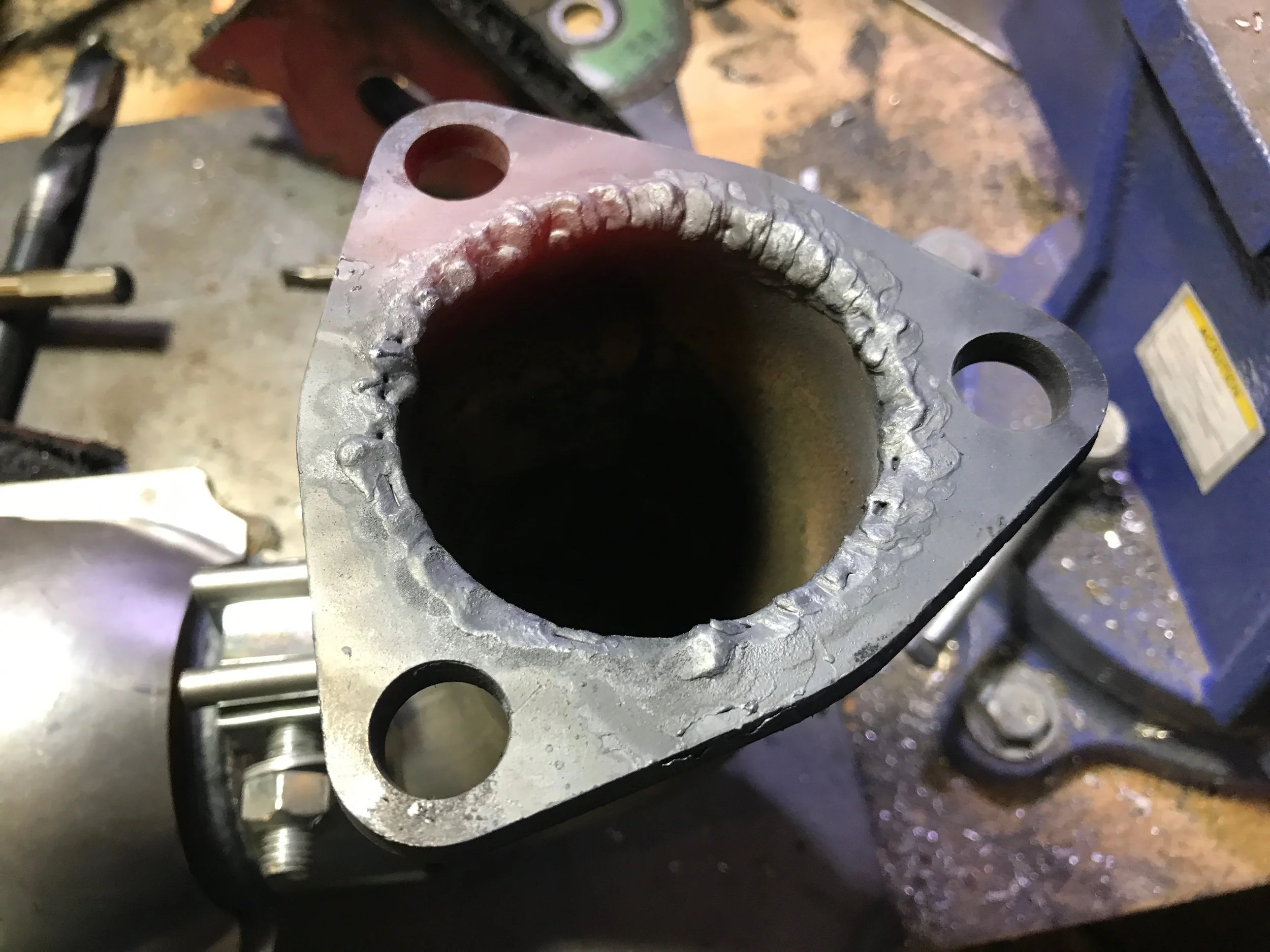 The just-welded flange on the end of the steel pipe.