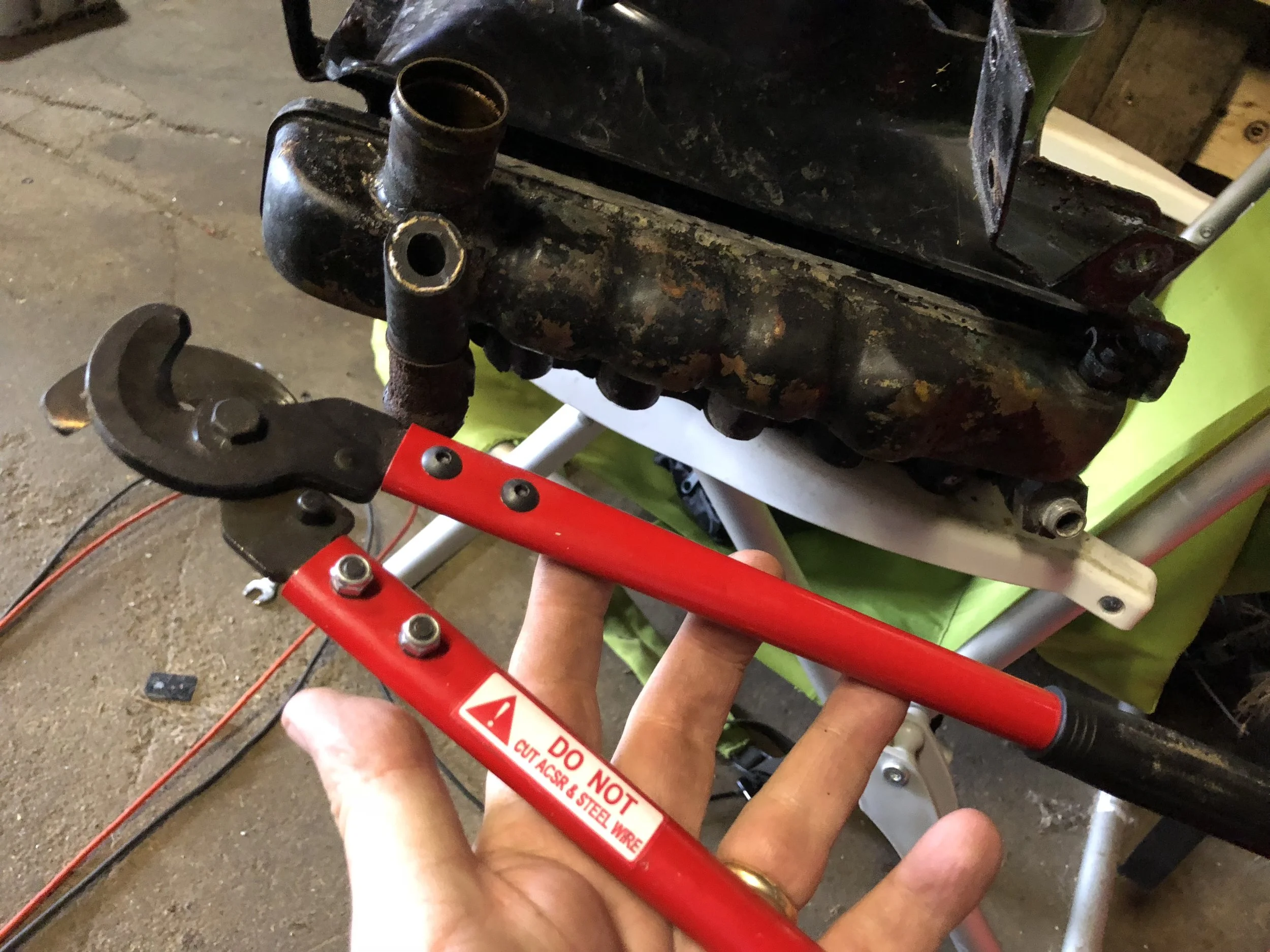 Fuel line cutters used to cut off the upper condenser line, visible sticking out from behind the radiator.